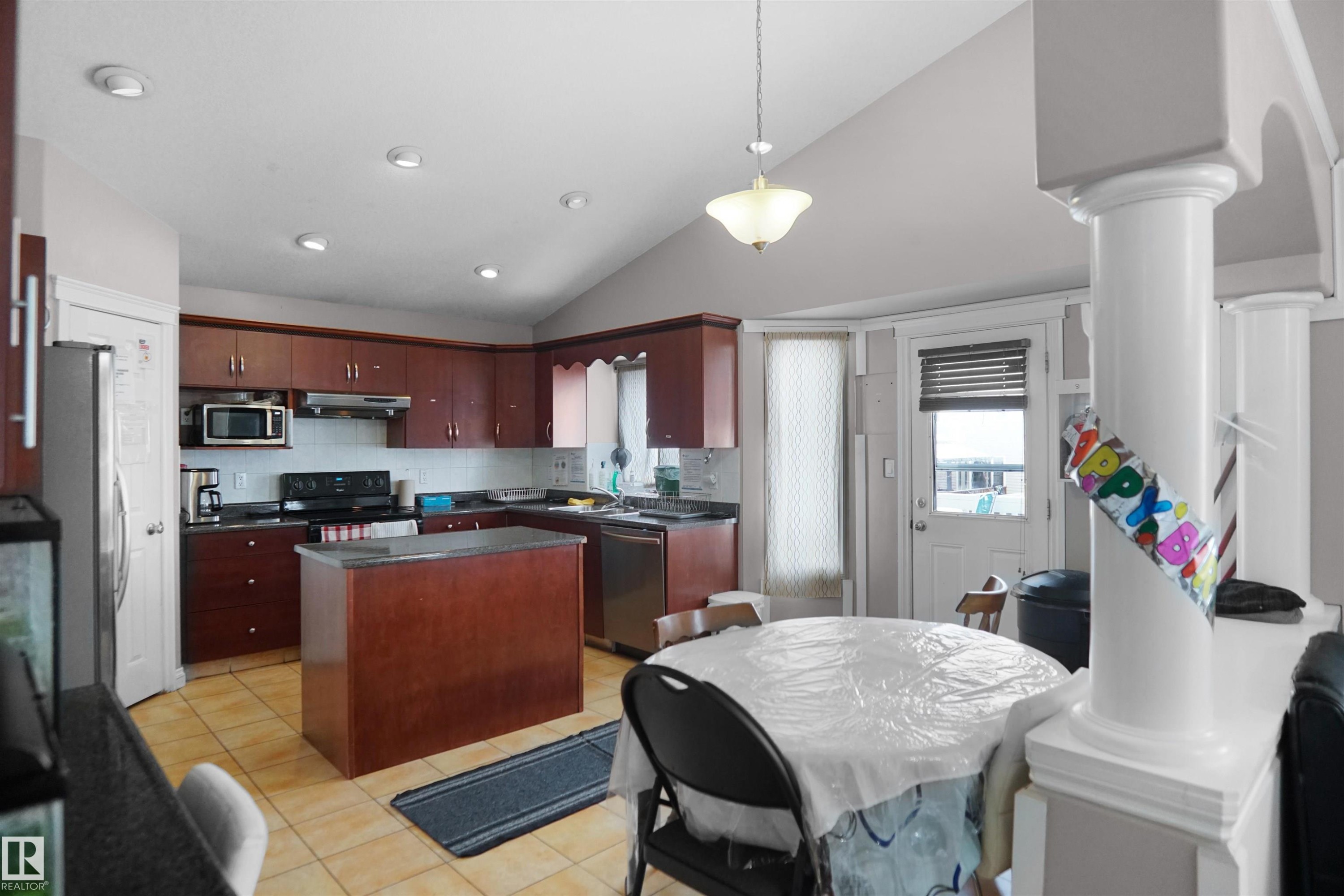 Spacious kitchen featuring rich wood cabinetry, dark countertops, a central island, and recessed lighting - 4816 155 Ave, Edmonton, AB
