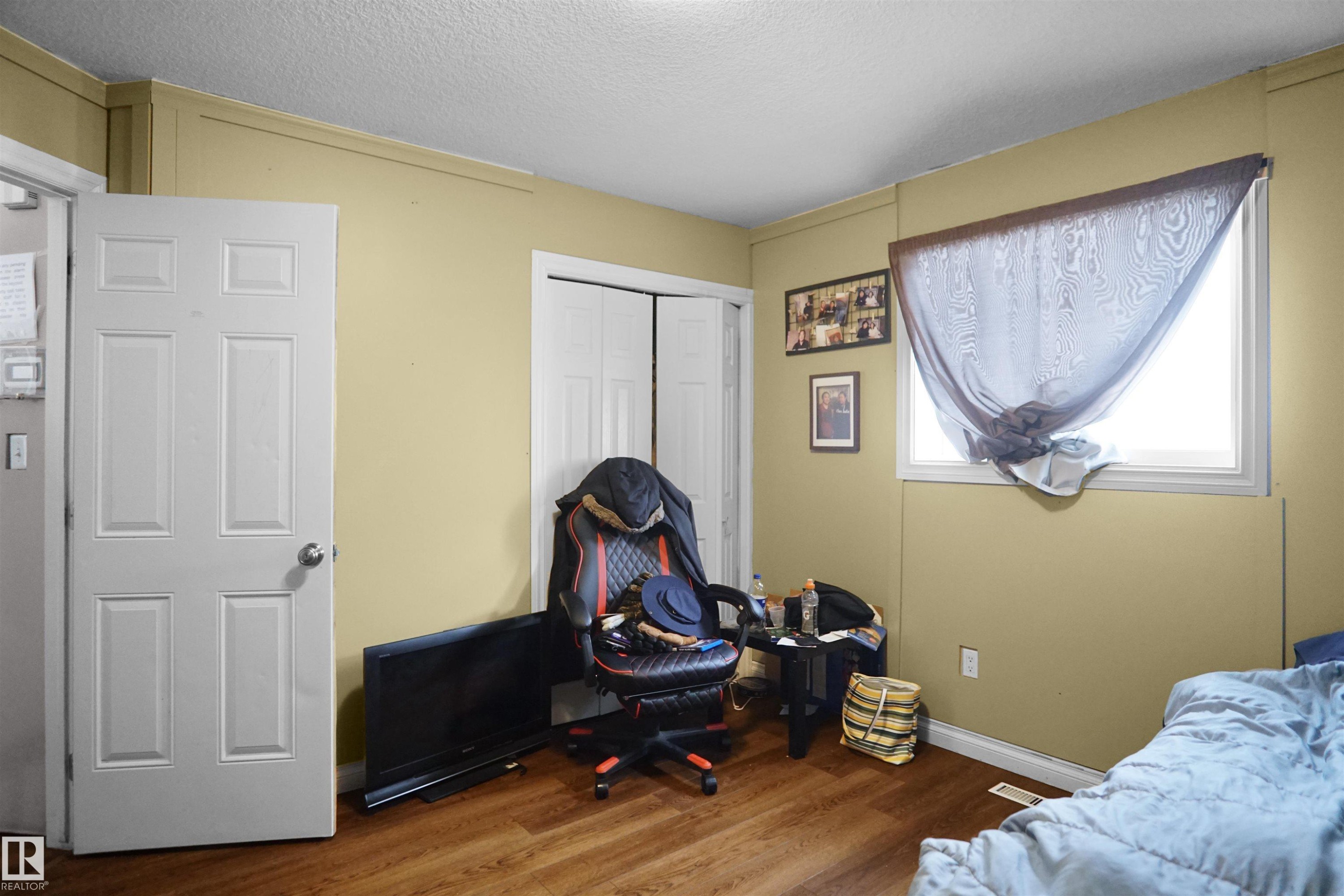 Room with wood-finish flooring, light-colored walls, and a white framed window - 4816 155 Ave, Edmonton, AB