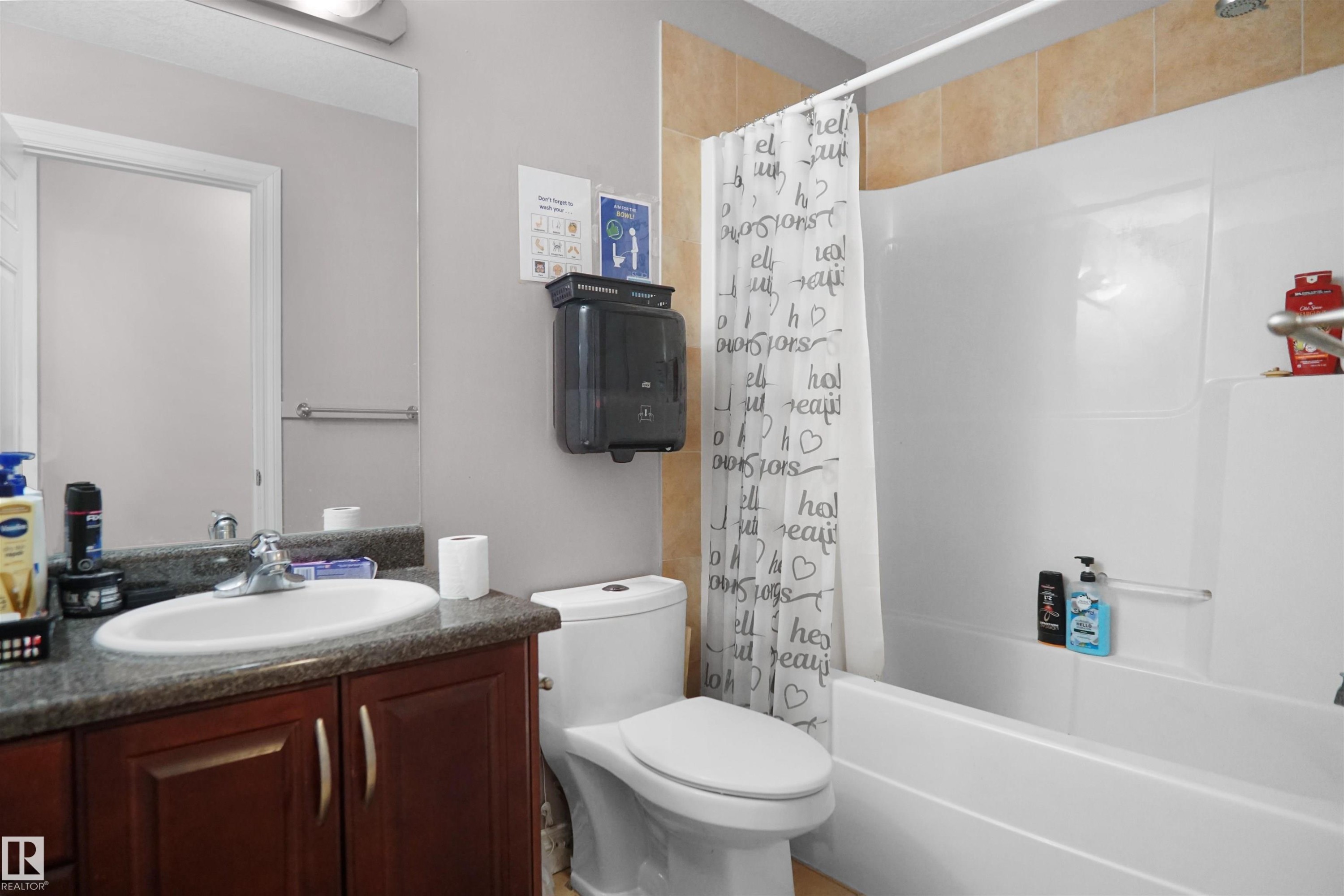 Bathroom featuring a vanity with dark wood-finish cabinetry, a white basin sink, and a speckled countertop - 4816 155 Ave, Edmonton, AB