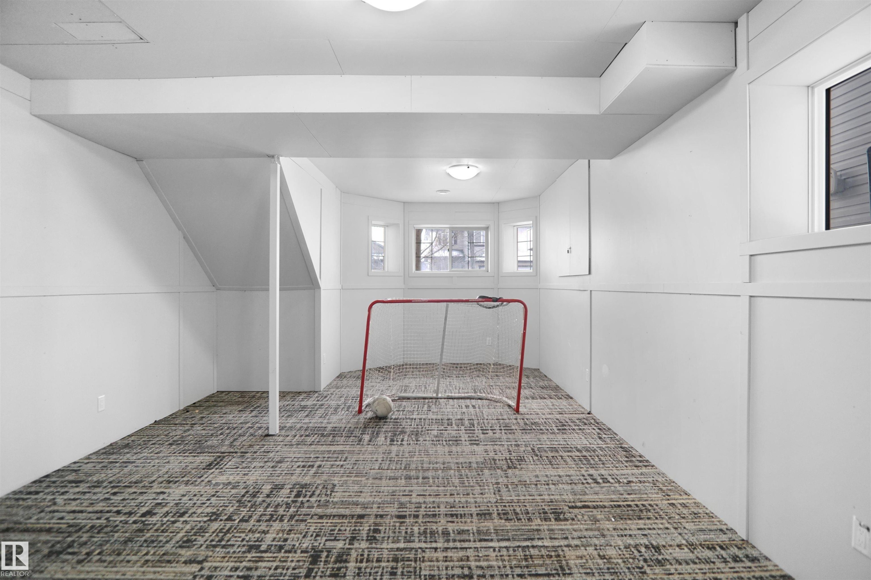 Finished lower level featuring textured carpet flooring, white paneled walls, recessed lighting, and multiple windows - 4816 155 Ave, Edmonton, AB