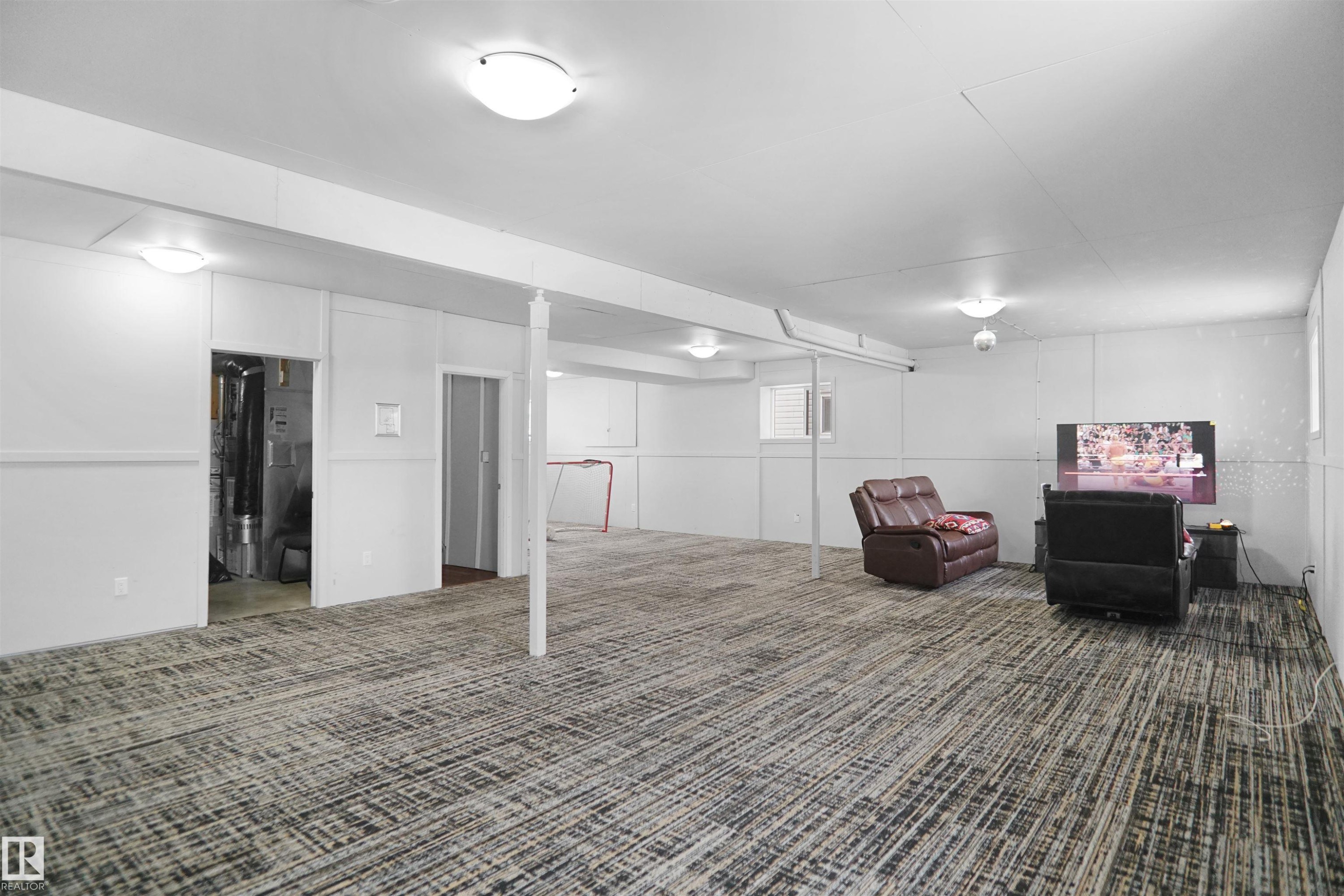 Expansive finished lower level featuring patterned carpet, white paneling, and ceiling-mounted dome lighting - 4816 155 Ave, Edmonton, AB