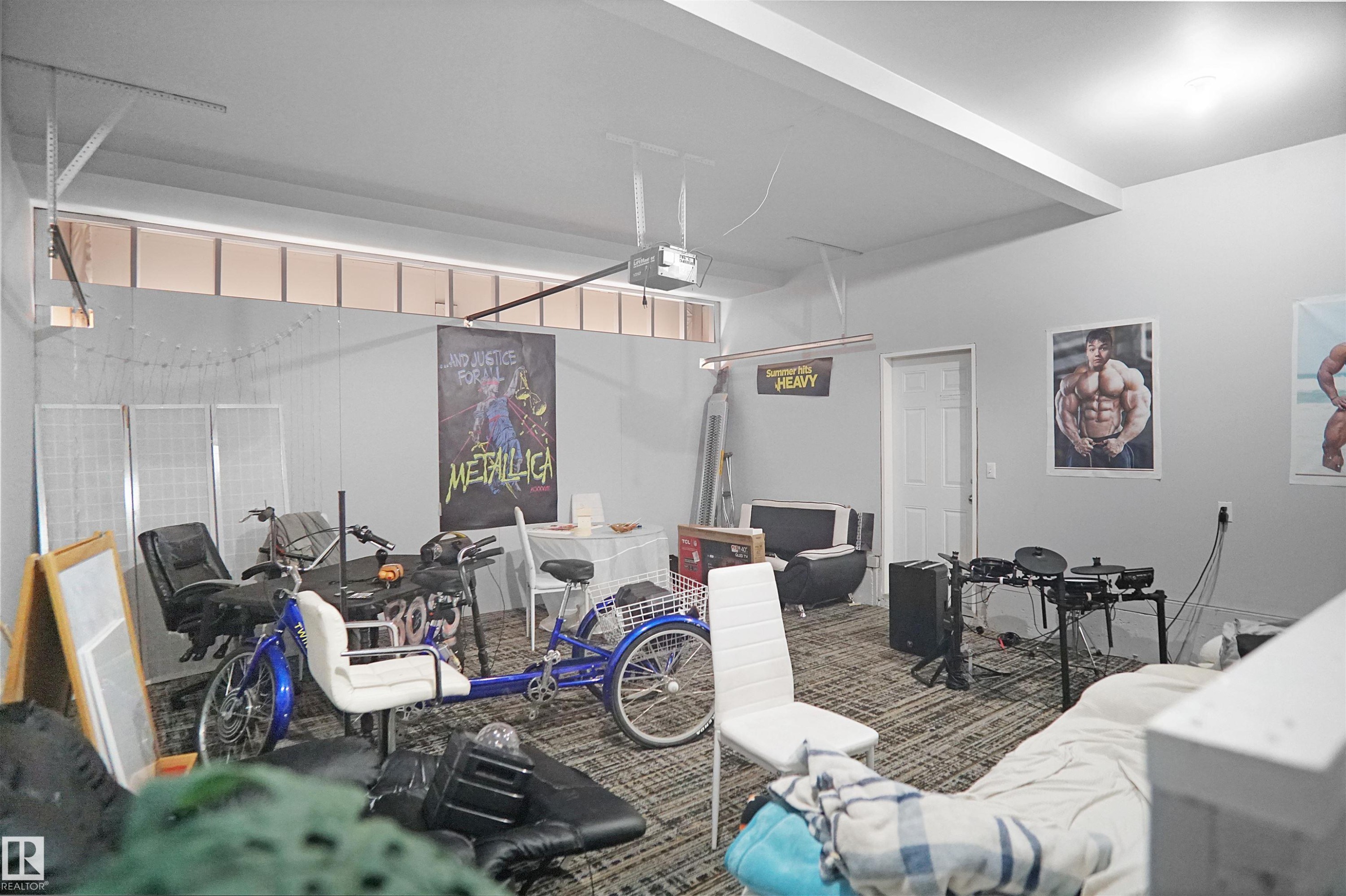 Interior space featuring light gray walls, a textured carpeted floor, and a white ceiling with an exposed garage door track - 4816 155 Ave, Edmonton, AB