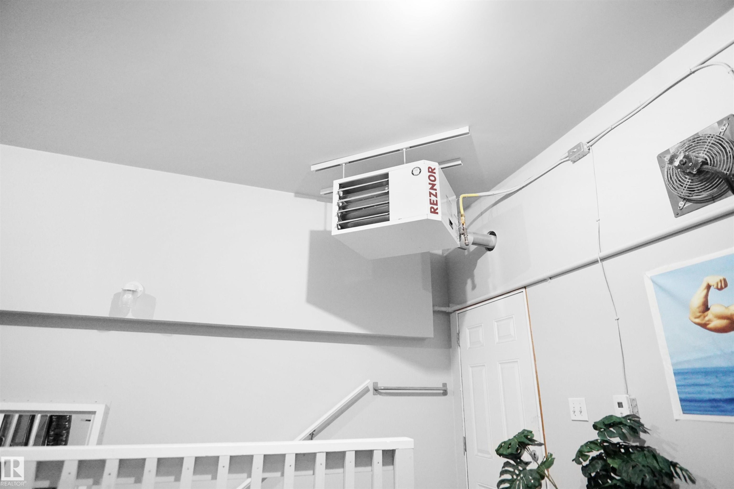 Ceiling-mounted Reznor heating unit with exposed conduit and wall-mounted exhaust fan - 4816 155 Ave, Edmonton, AB
