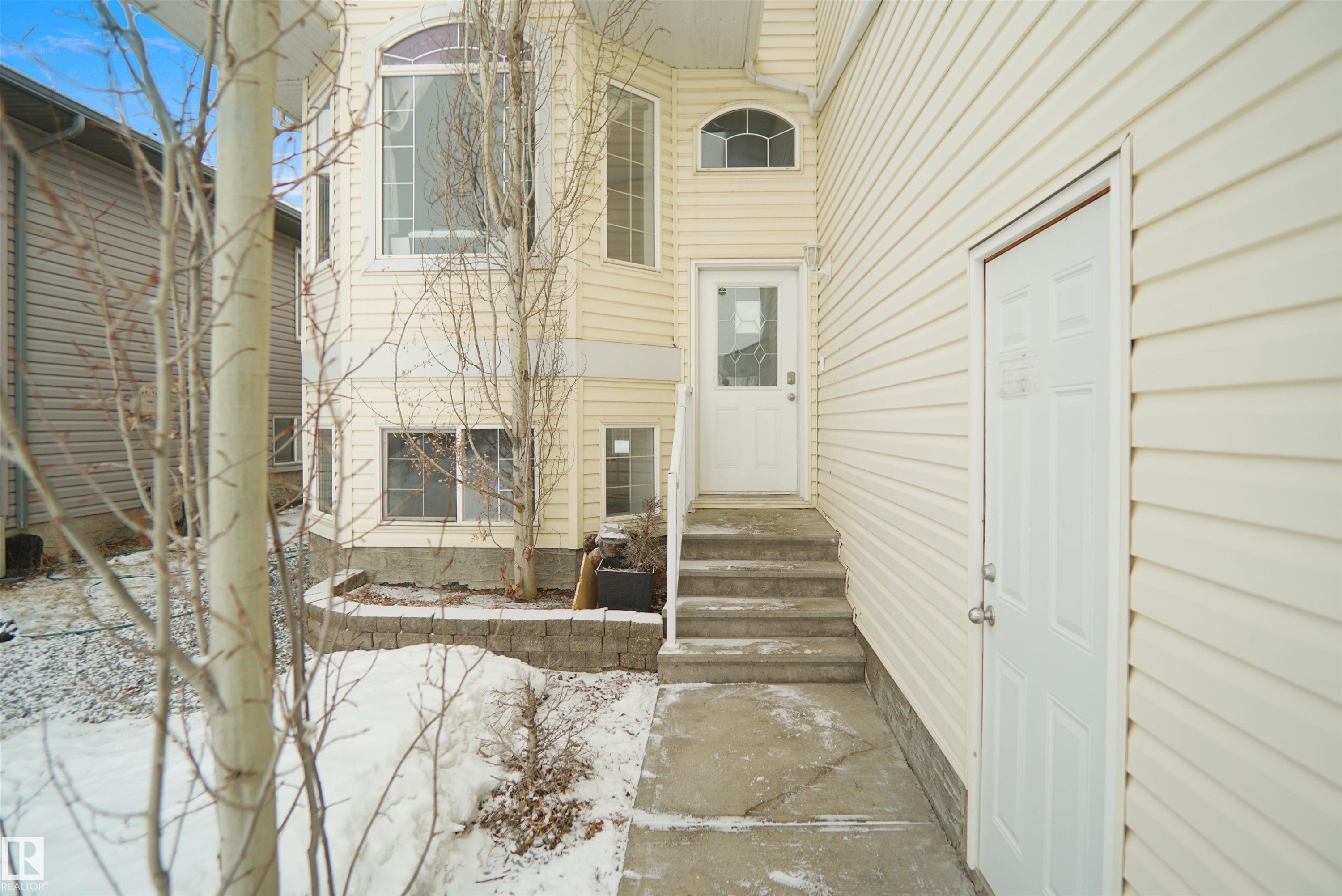 Cream-colored siding exterior featuring multiple windows, including an arched window and a large bay window - 4816 155 Ave, Edmonton, AB