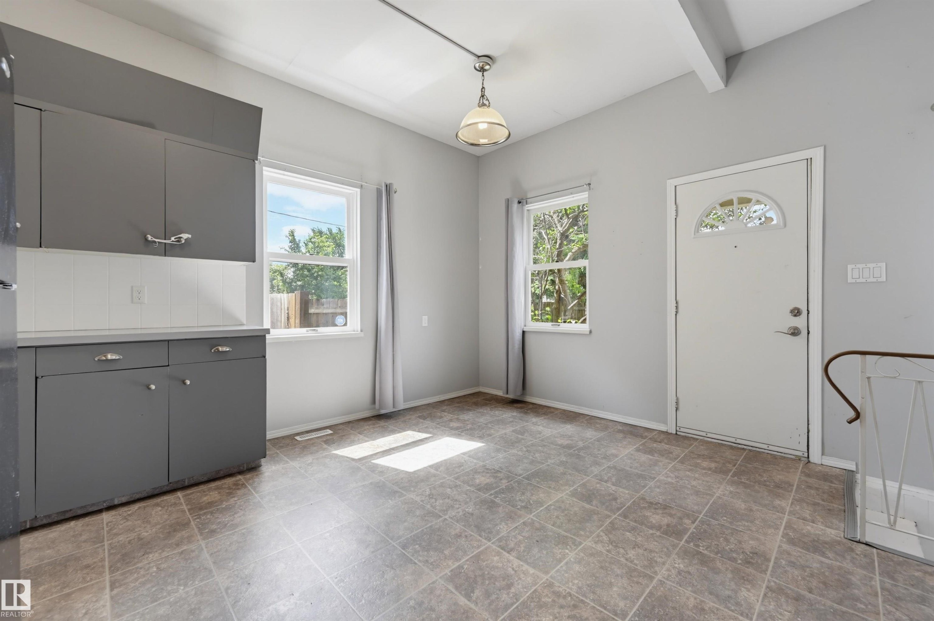 Kitchen area featuring dark gray cabinetry with chrome hardware, a white subway tile backsplash, and light gray countertops - 11450 71 Street Nw, Edmonton, AB