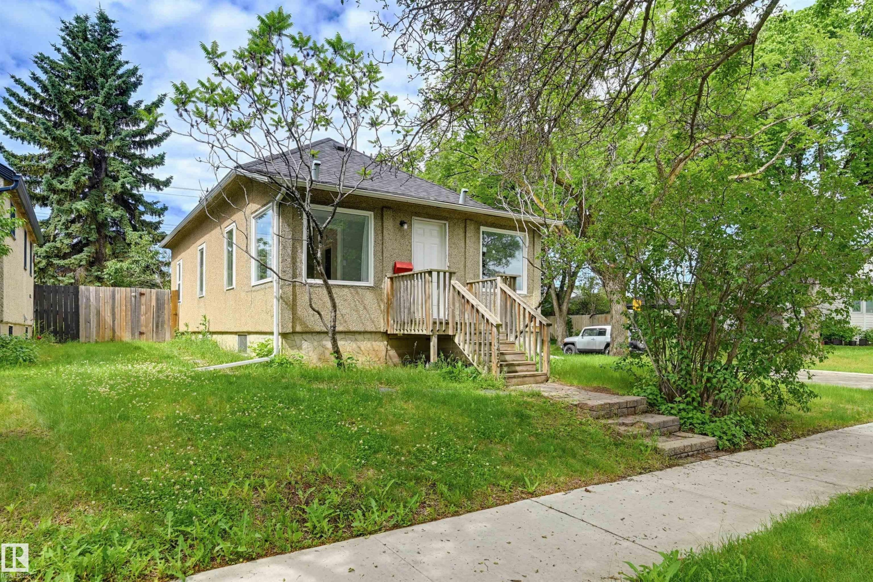 Property exterior featuring stucco siding and a front porch with wood railings - 11450 71 Street Nw, Edmonton, AB