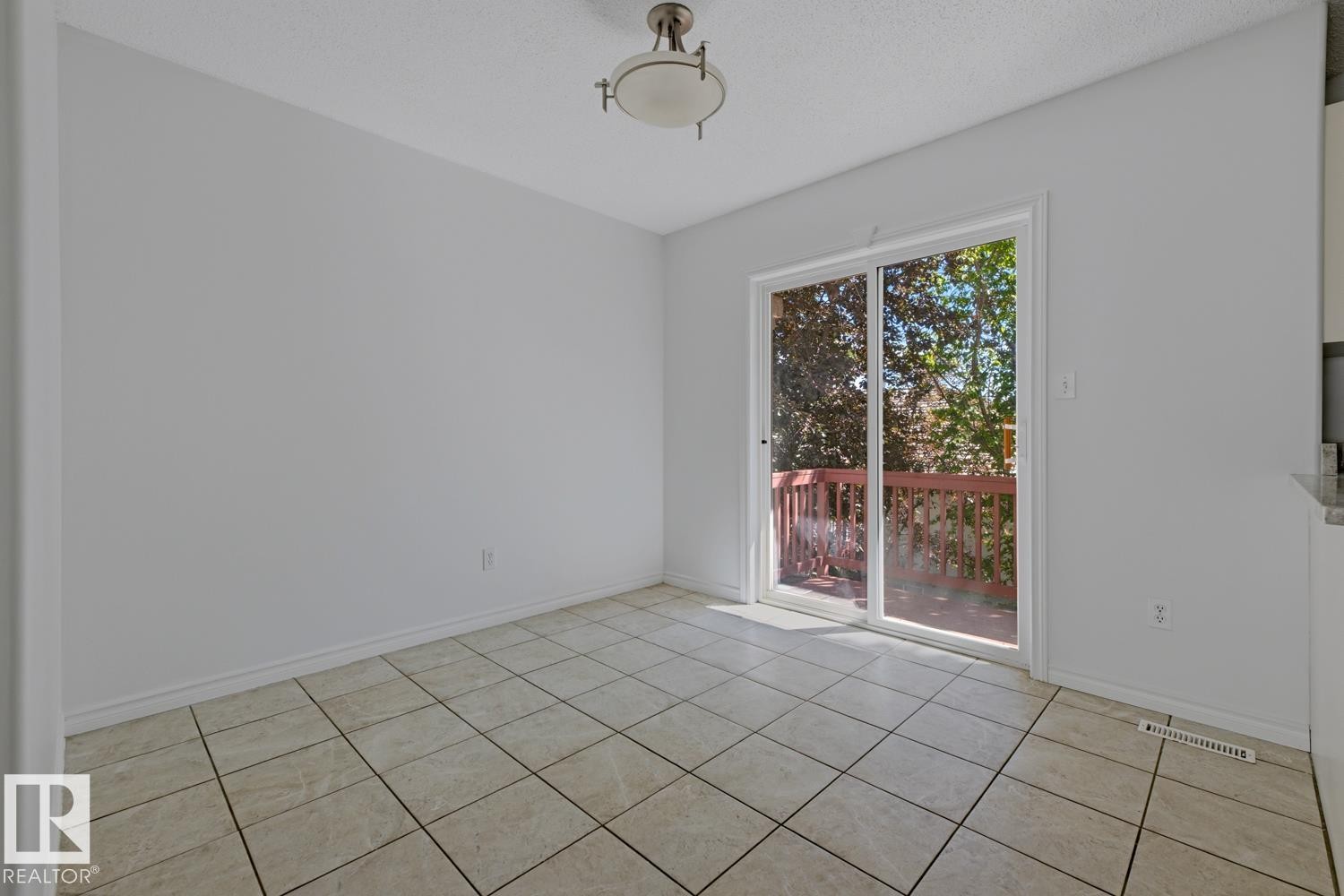 Room featuring light-colored tile flooring and a sliding glass door - 6 1237 Carter Crest Road, Edmonton, AB