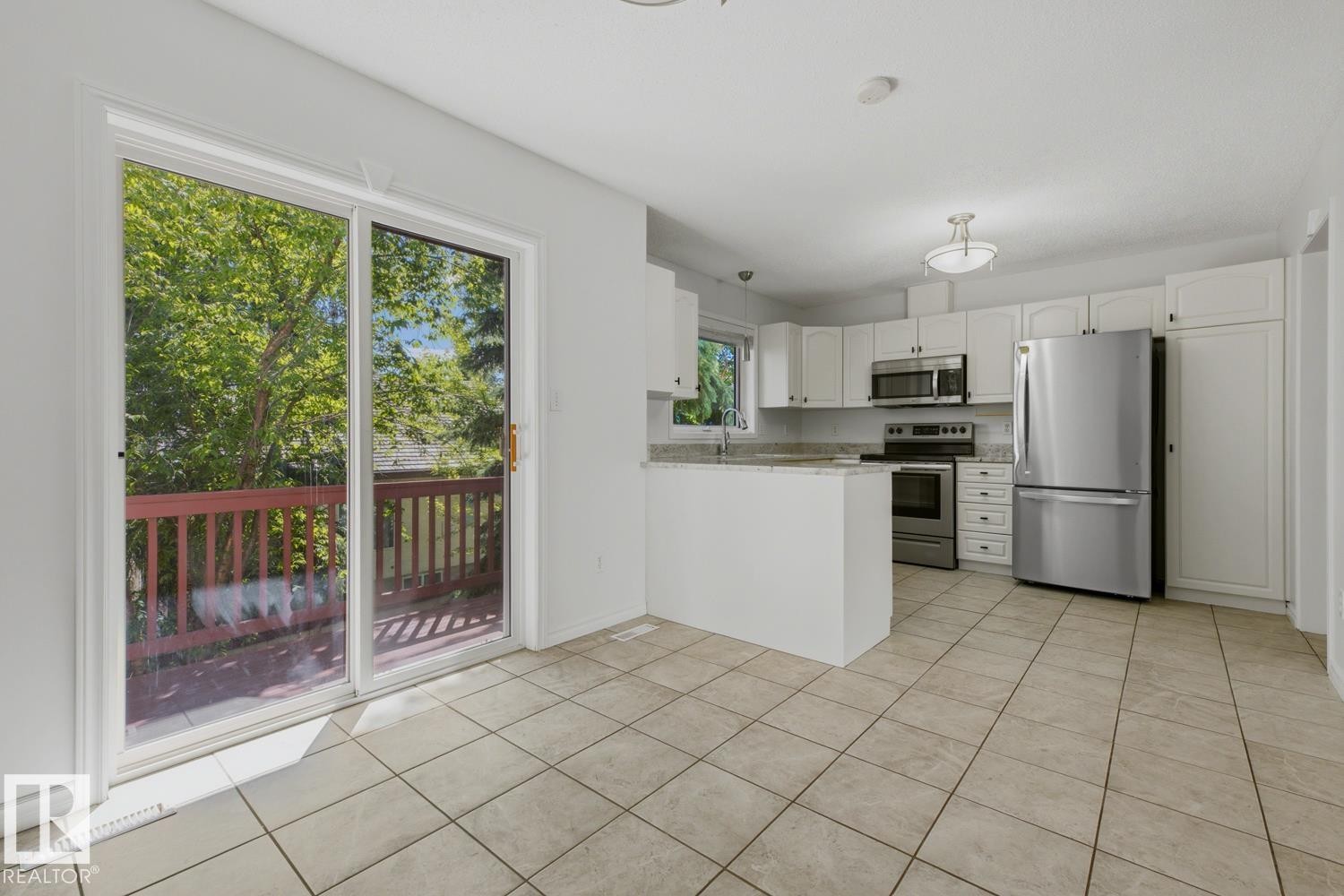 Kitchen featuring stainless steel appliances, white cabinetry, and a light-toned tile floor - 6 1237 Carter Crest Road, Edmonton, AB