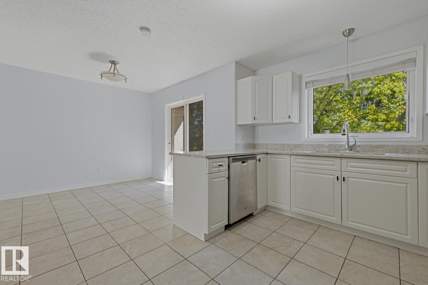 Open-concept kitchen and dining area featuring white cabinetry, light-toned granite countertops, and stainless steel dishwasher - 6 1237 Carter Crest Road, Edmonton, AB