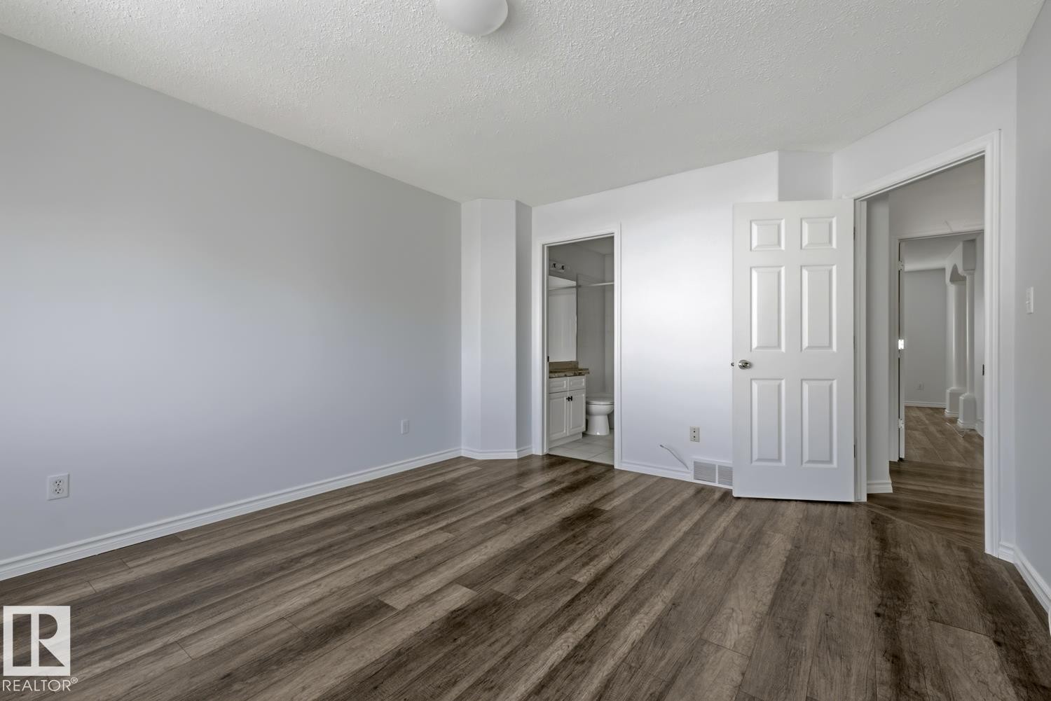 Spacious room featuring wood-finish flooring, light grey walls, and white trim - 6 1237 Carter Crest Road, Edmonton, AB