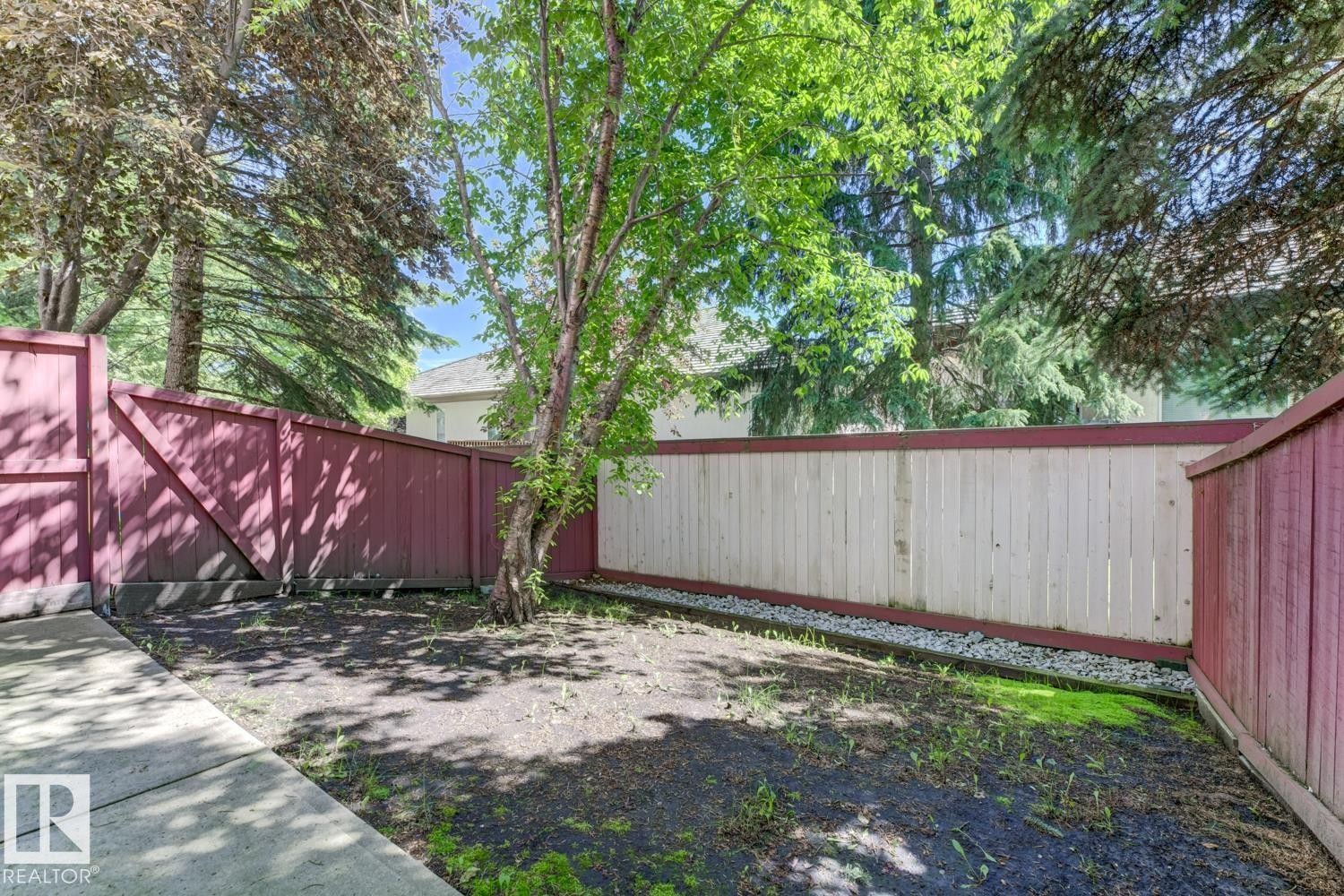 Fenced yard area featuring a combination of red and light-toned vertical plank fencing - 6 1237 Carter Crest Road, Edmonton, AB