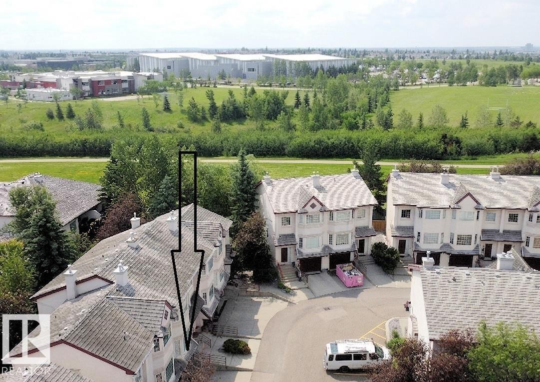 Townhome property featuring a light-colored stucco exterior, attached garage, and a gabled roofline - 6 1237 Carter Crest Road, Edmonton, AB
