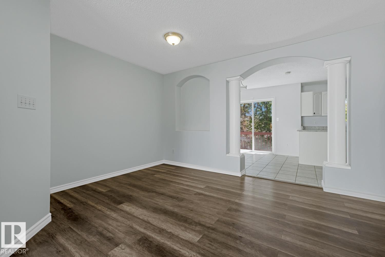 Spacious room featuring wood-finish flooring, light grey walls, white baseboards, and a ceiling-mounted light fixture - 6 1237 Carter Crest Road, Edmonton, AB