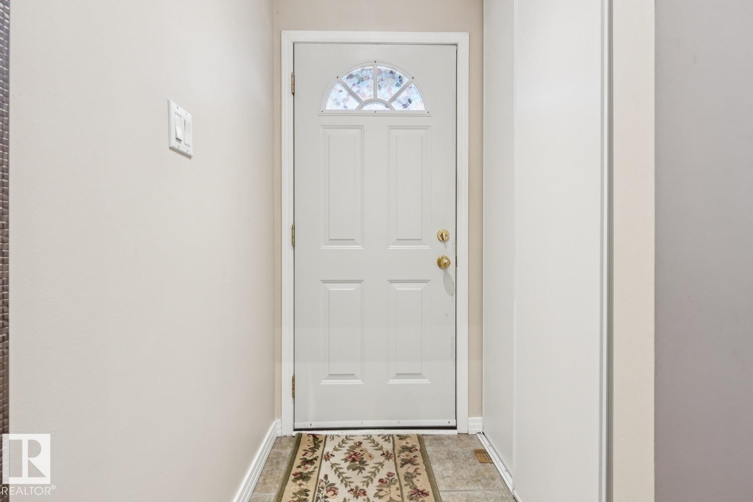 White paneled door with an arched glass insert and brass hardware - 3015 131 Avenue, Edmonton, AB