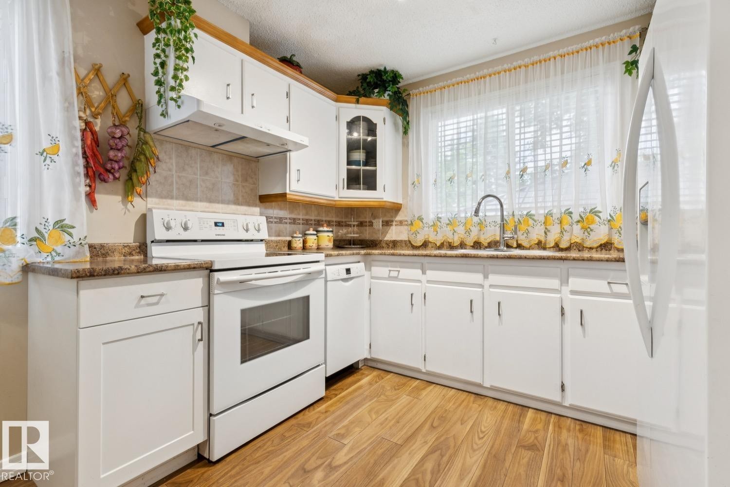 Kitchen featuring white cabinetry, wood-finish flooring, and a window above the sink - 3015 131 Avenue, Edmonton, AB
