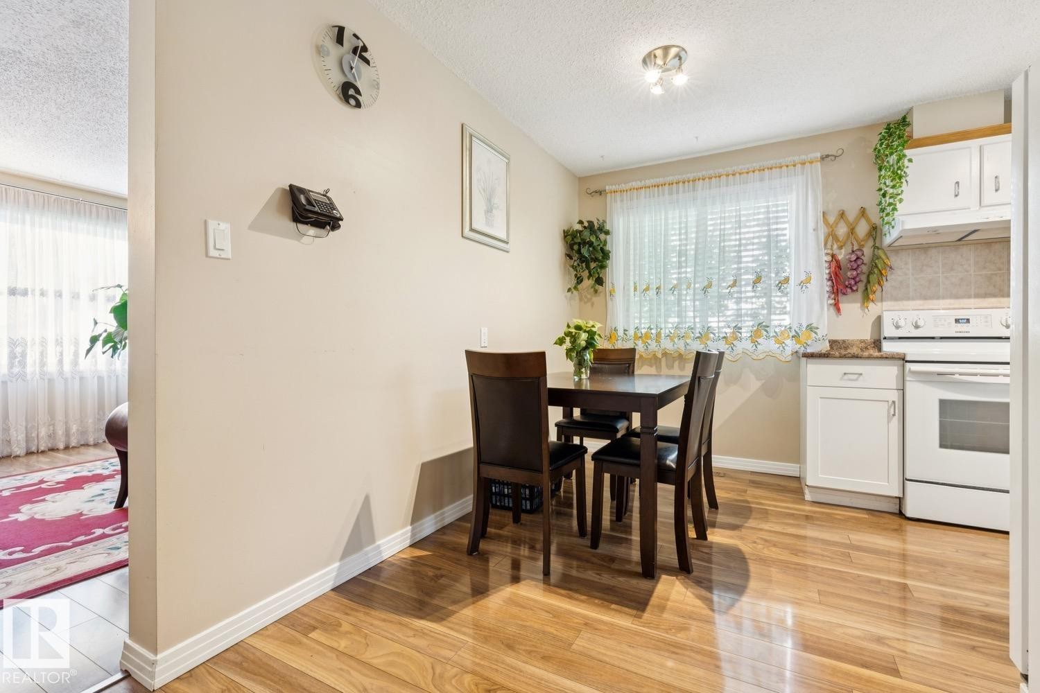 Dining area featuring wood-finish flooring, a window with horizontal blinds, and white base cabinetry with a light-colored countertop - 3015 131 Avenue, Edmonton, AB