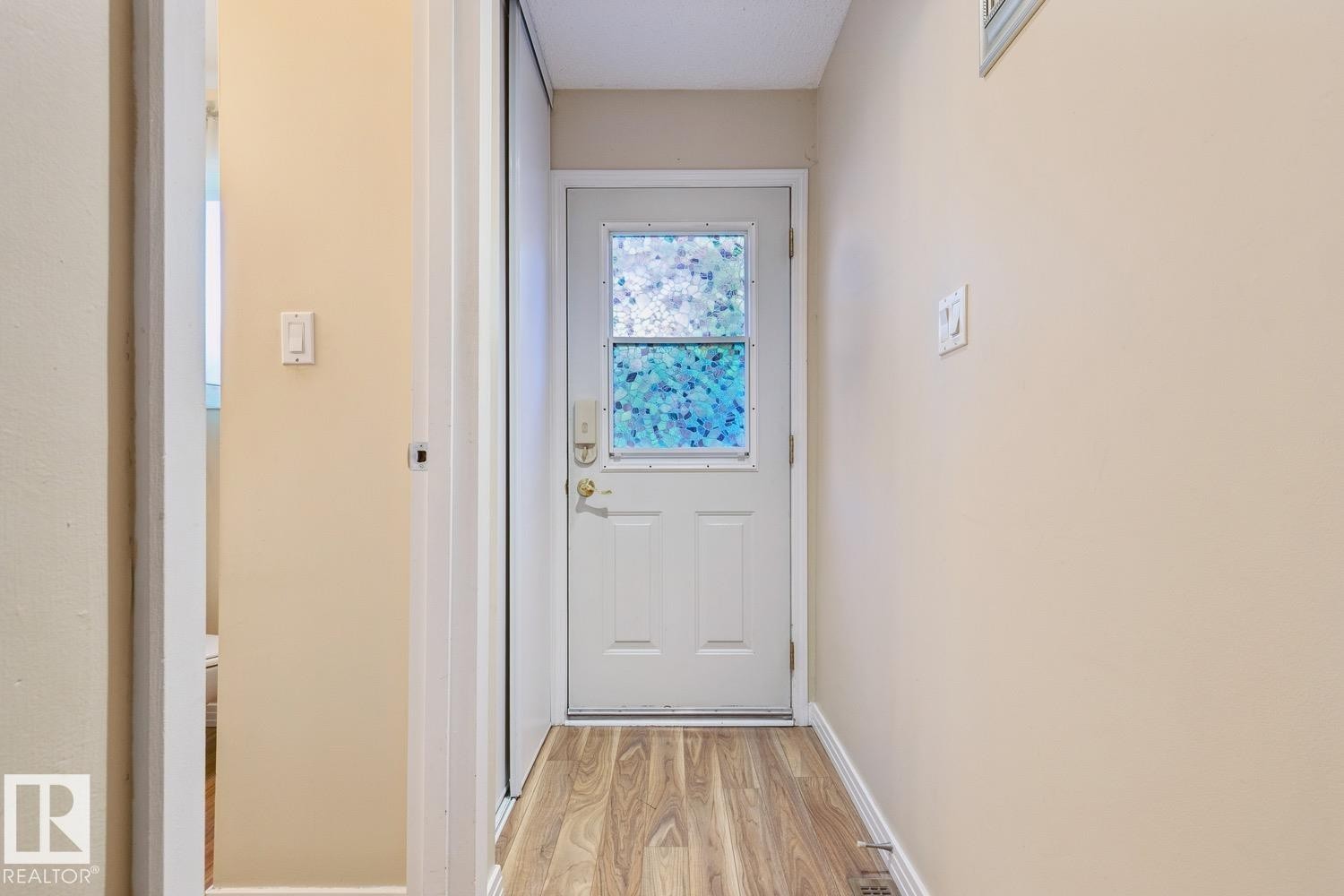 Entryway featuring a white door with frosted glass, wood-finish flooring, and neutral wall paint - 3015 131 Avenue, Edmonton, AB
