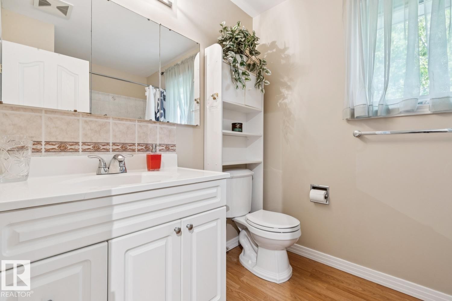 Bathroom featuring a white vanity with integrated sink, coordinating wall-mounted storage cabinet, and a multi-panel mirrored medicine cabinet - 3015 131 Avenue, Edmonton, AB