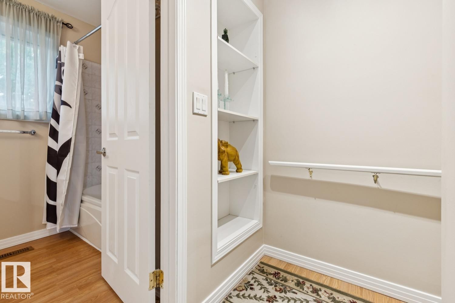 Bathroom featuring light beige walls, wood-finish flooring, and a built-in shelving unit - 3015 131 Avenue, Edmonton, AB
