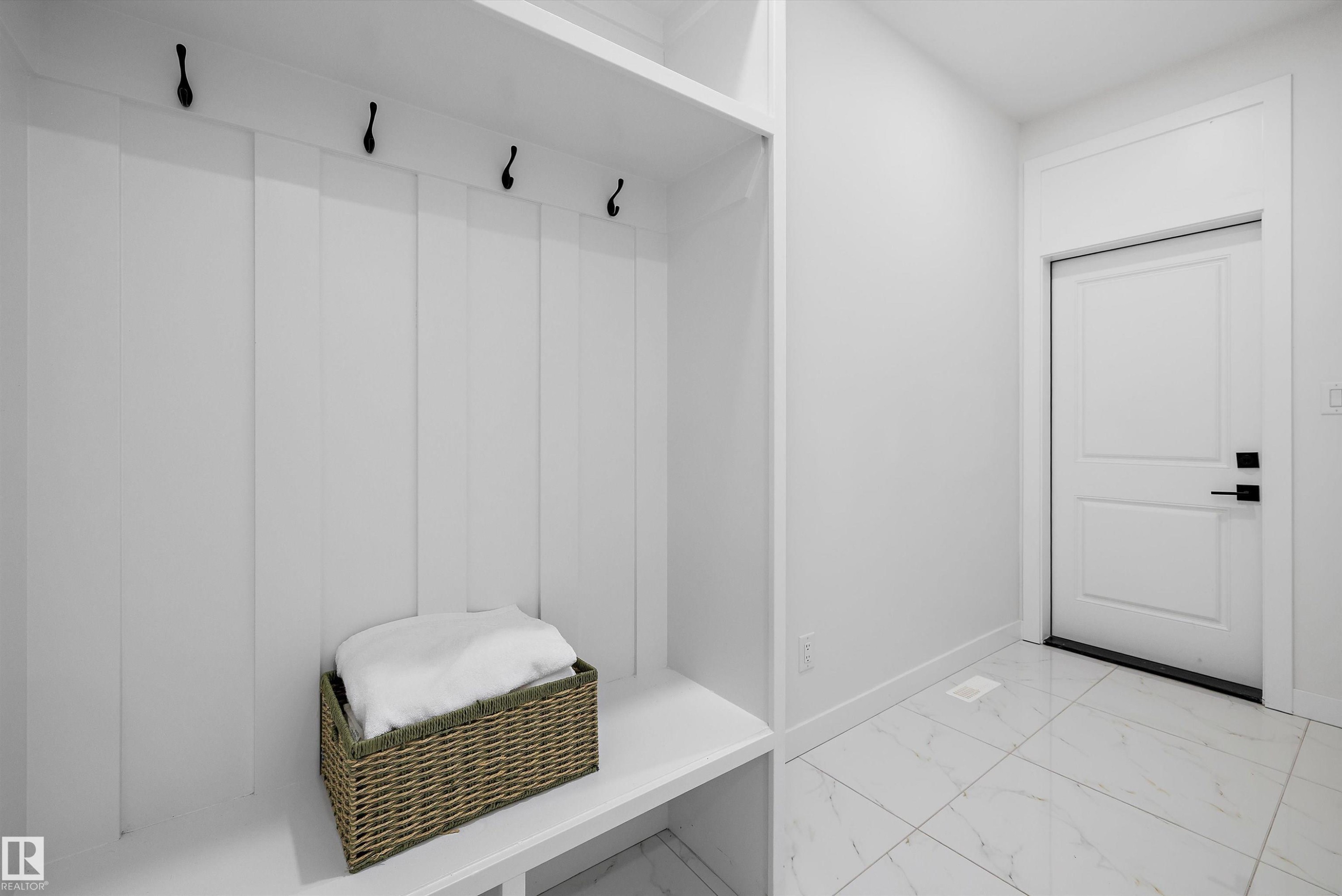 Built-in mudroom bench with upper storage and black wall-mounted hooks - 403 Pine Point, Leduc, AB