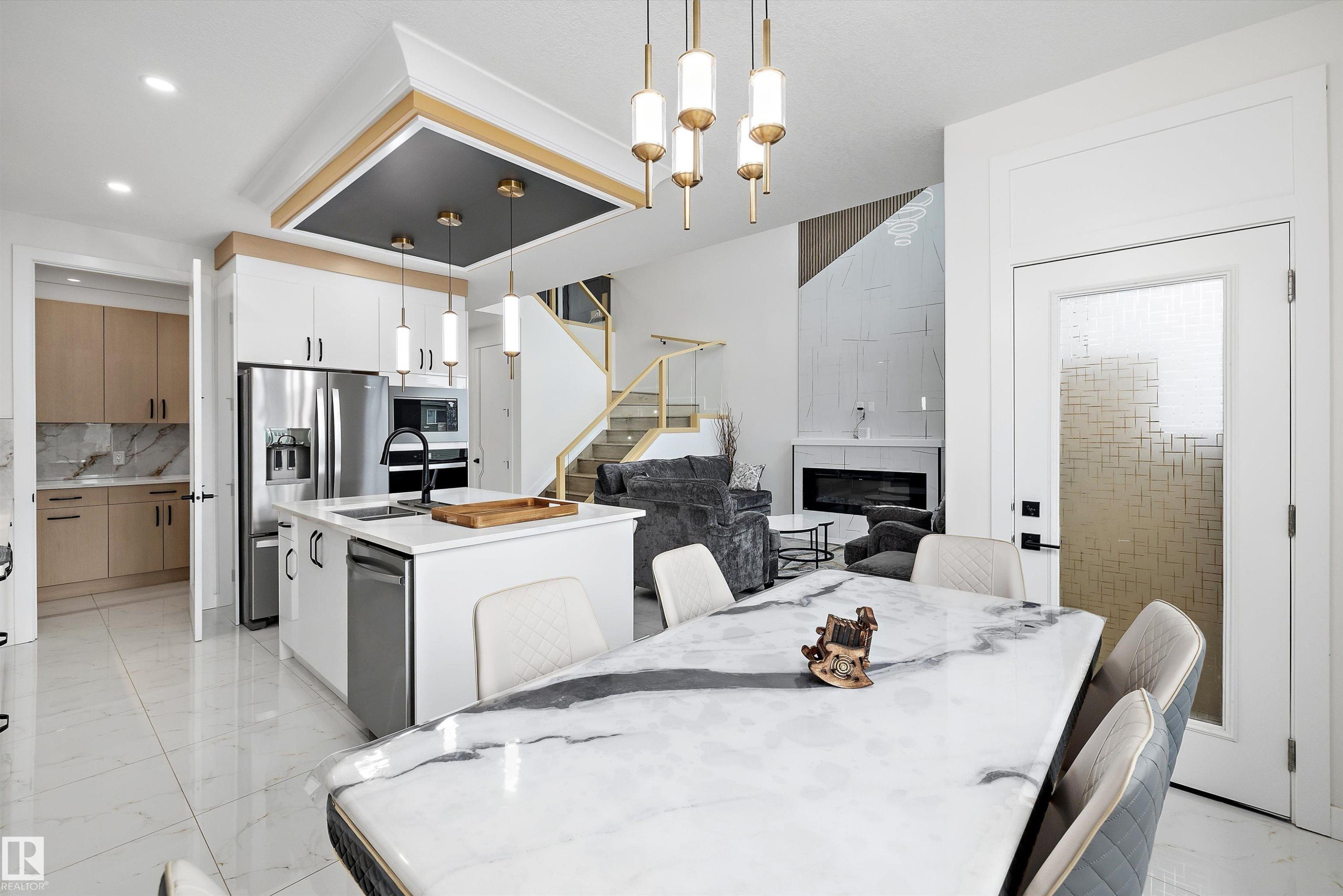 Open concept living area featuring a kitchen island with sink, stainless steel appliances, and wood-finish flooring - 403 Pine Point, Leduc, AB