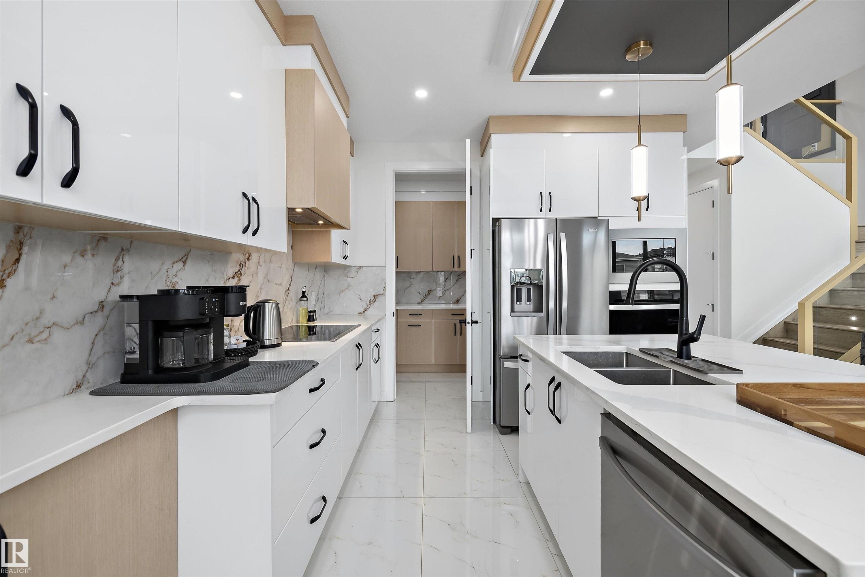 Modern kitchen featuring white and wood-finish cabinetry, quartz countertops, a stone-look backsplash, and integrated stainless steel appliances - 403 Pine Point, Leduc, AB