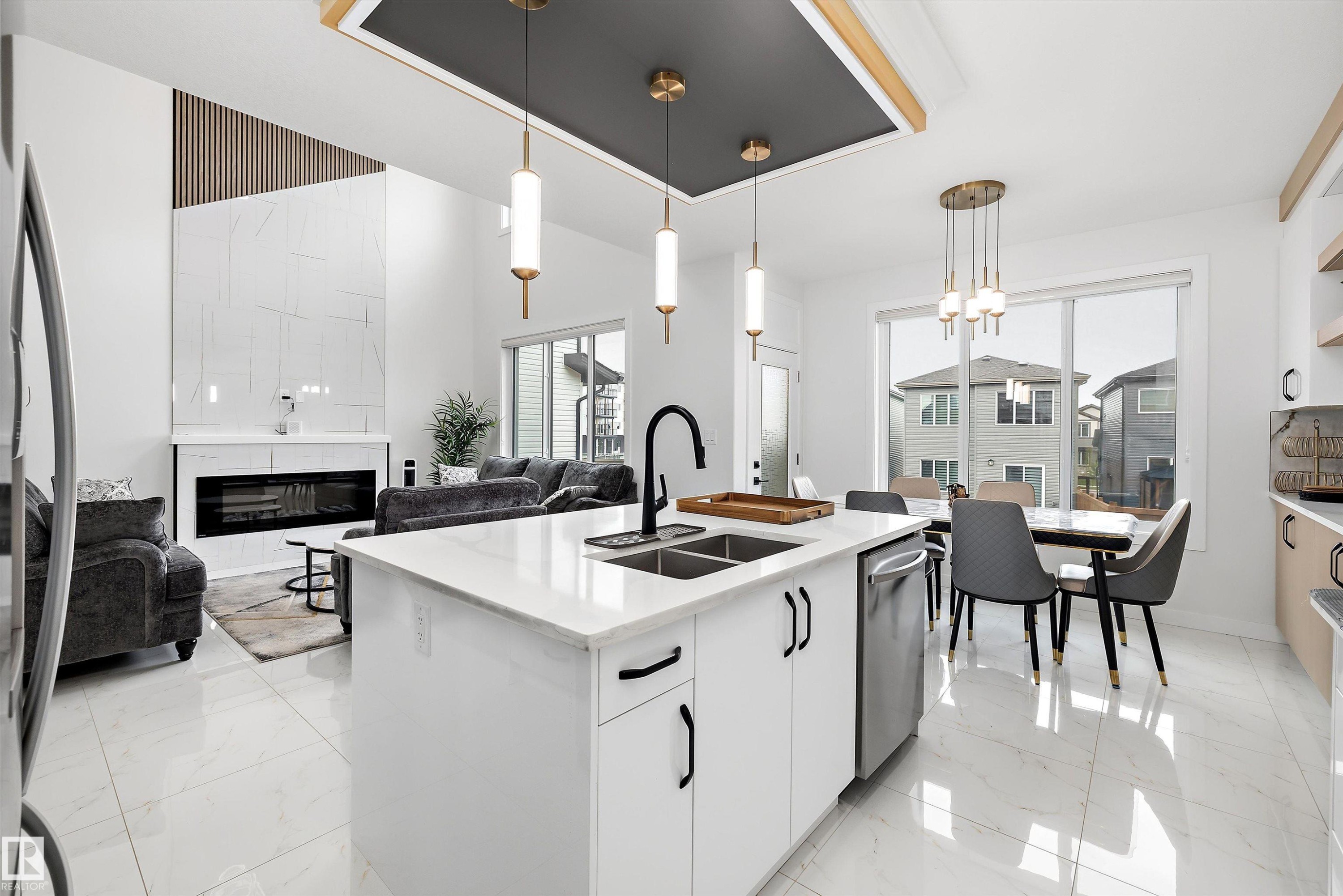 Open-concept living space featuring a central kitchen island with a double basin sink and stainless steel dishwasher - 403 Pine Point, Leduc, AB