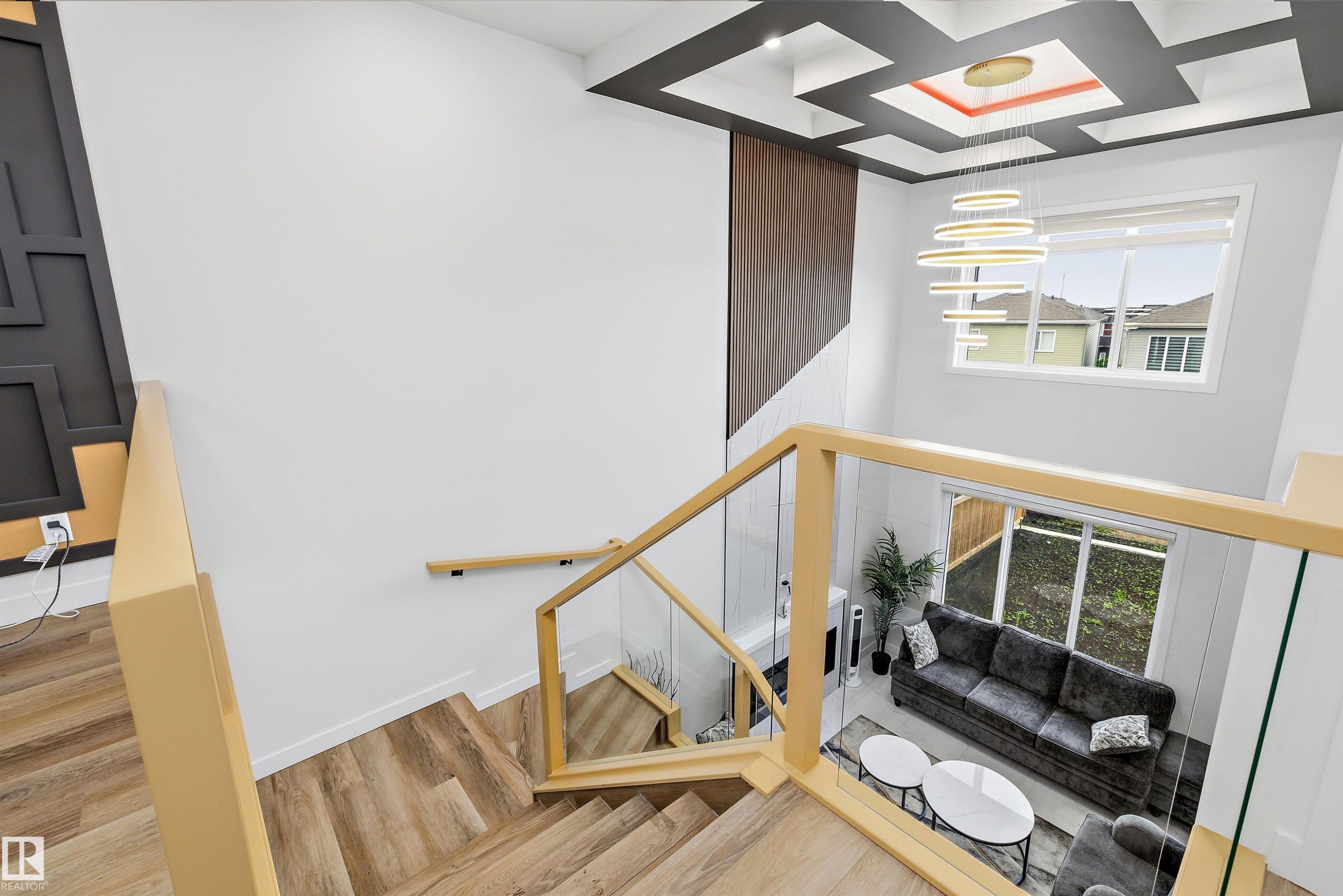 Grand staircase with wood-finish treads and glass railings - 403 Pine Point, Leduc, AB