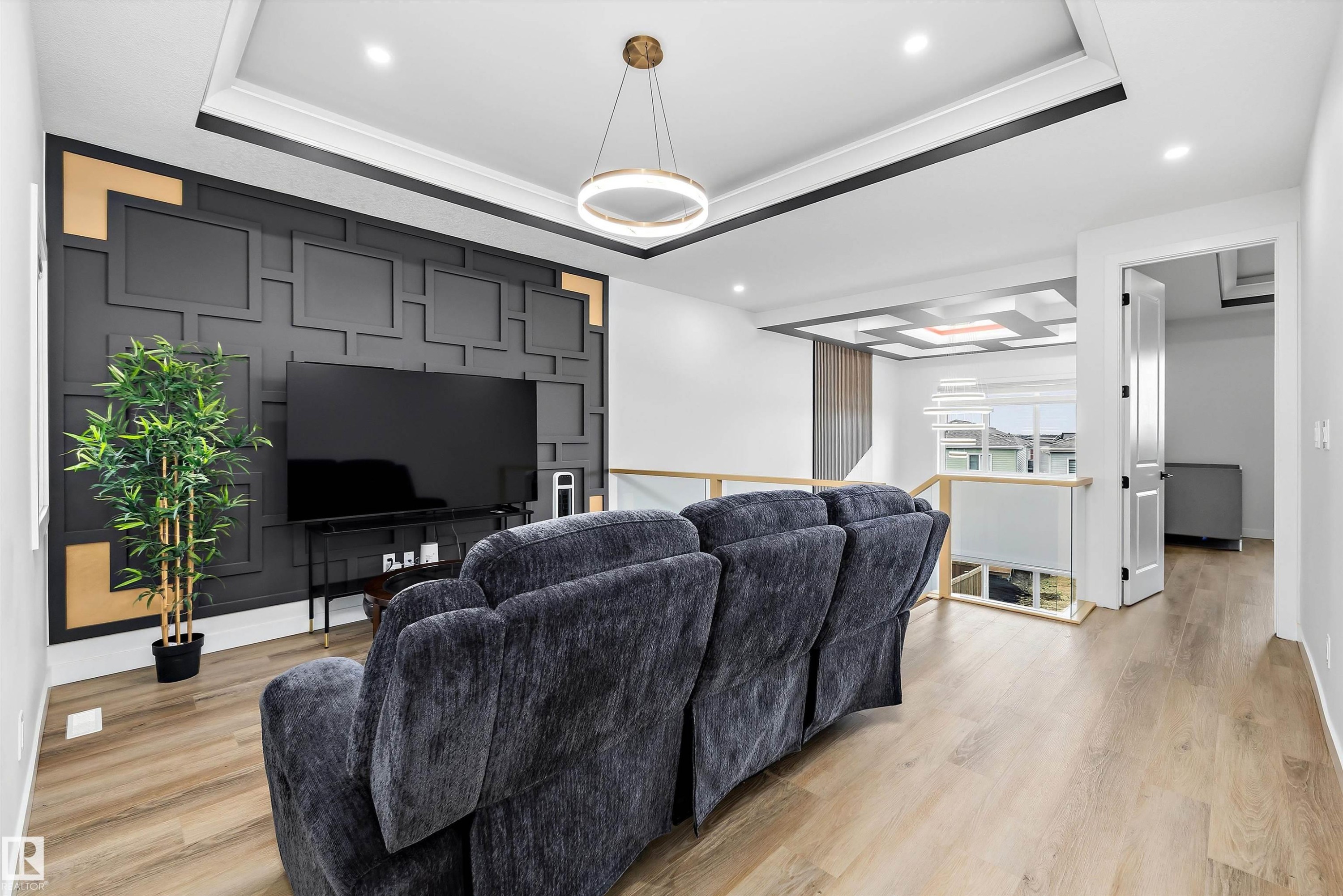 Living space featuring a striking accent wall with geometric paneling and gold-toned accents - 403 Pine Point, Leduc, AB