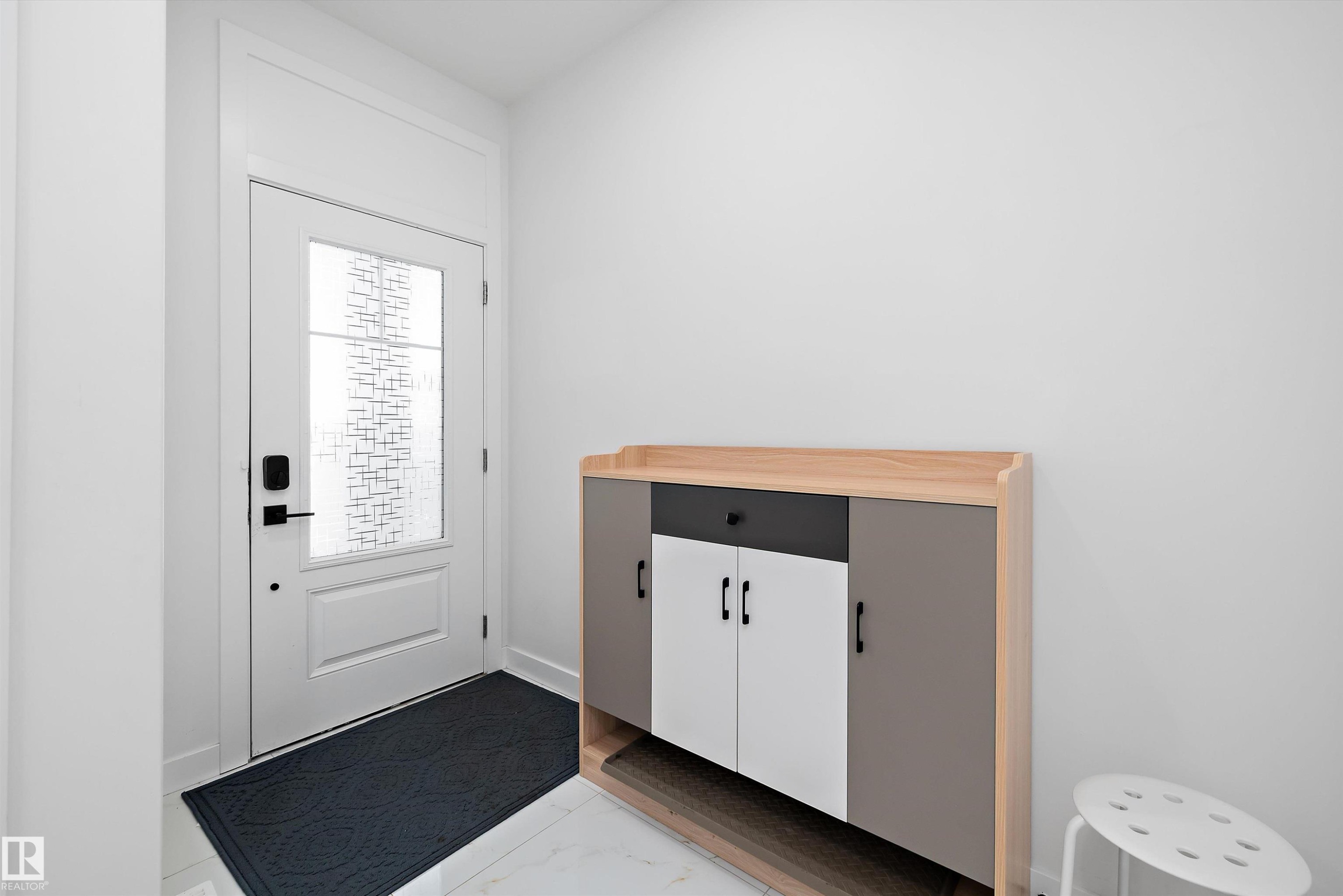 Entryway featuring a white paneled door with decorative glass, modern black hardware, and a transom window above - 403 Pine Point, Leduc, AB