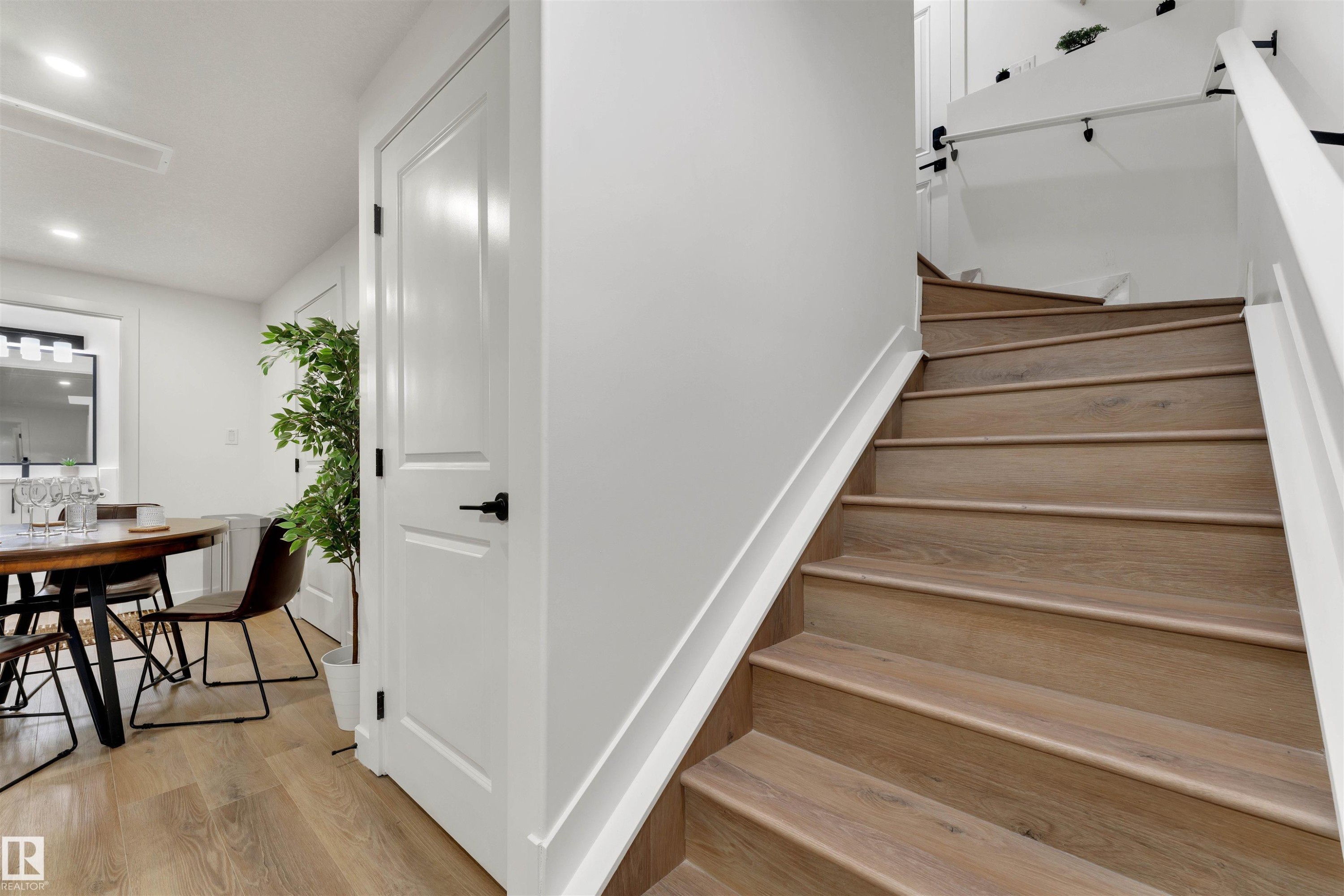 Staircase featuring wood-finish treads and white risers with a contrasting white handrail - 403 Pine Point, Leduc, AB