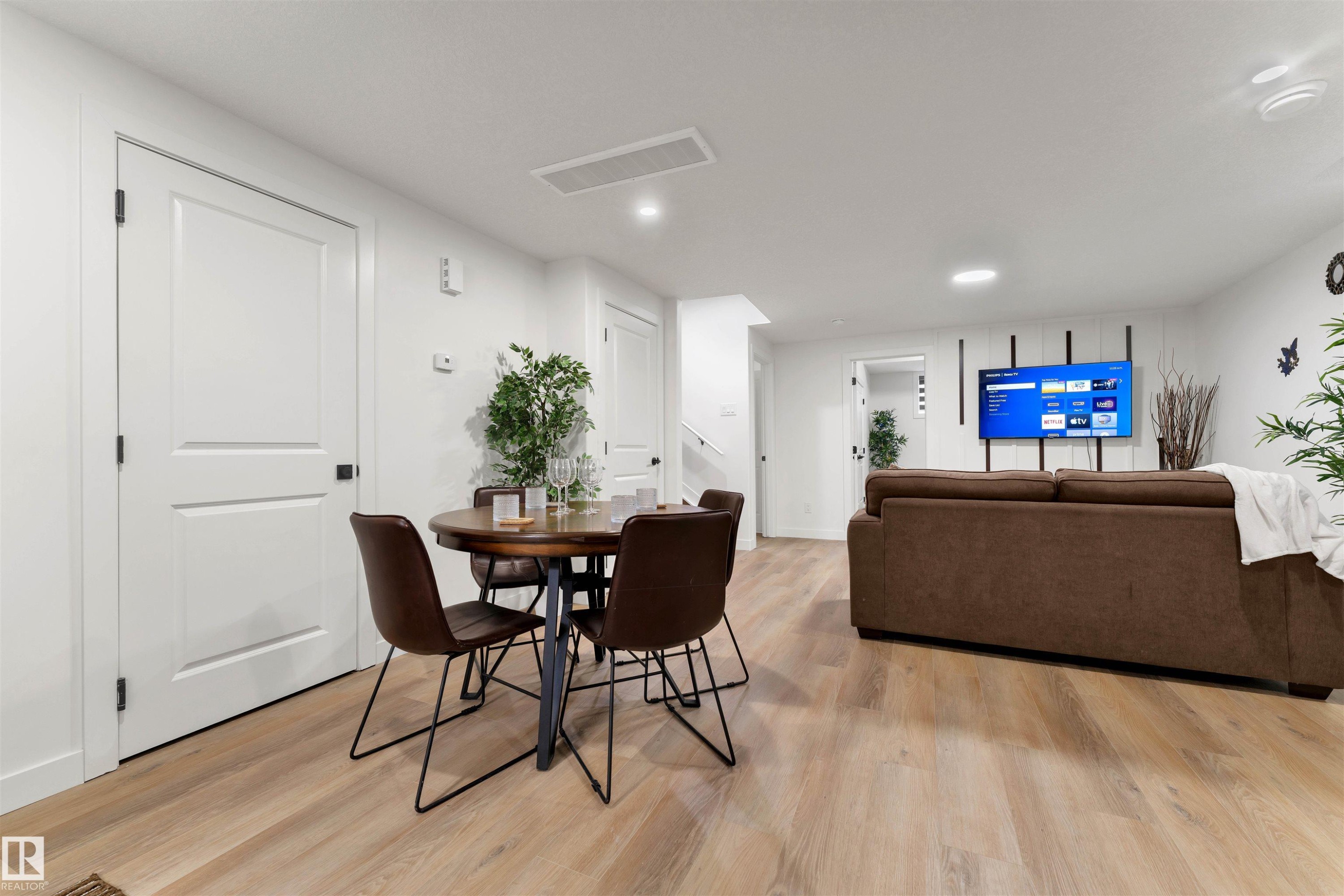 Spacious room featuring light wood-finish flooring, recessed lighting, and white baseboards - 403 Pine Point, Leduc, AB