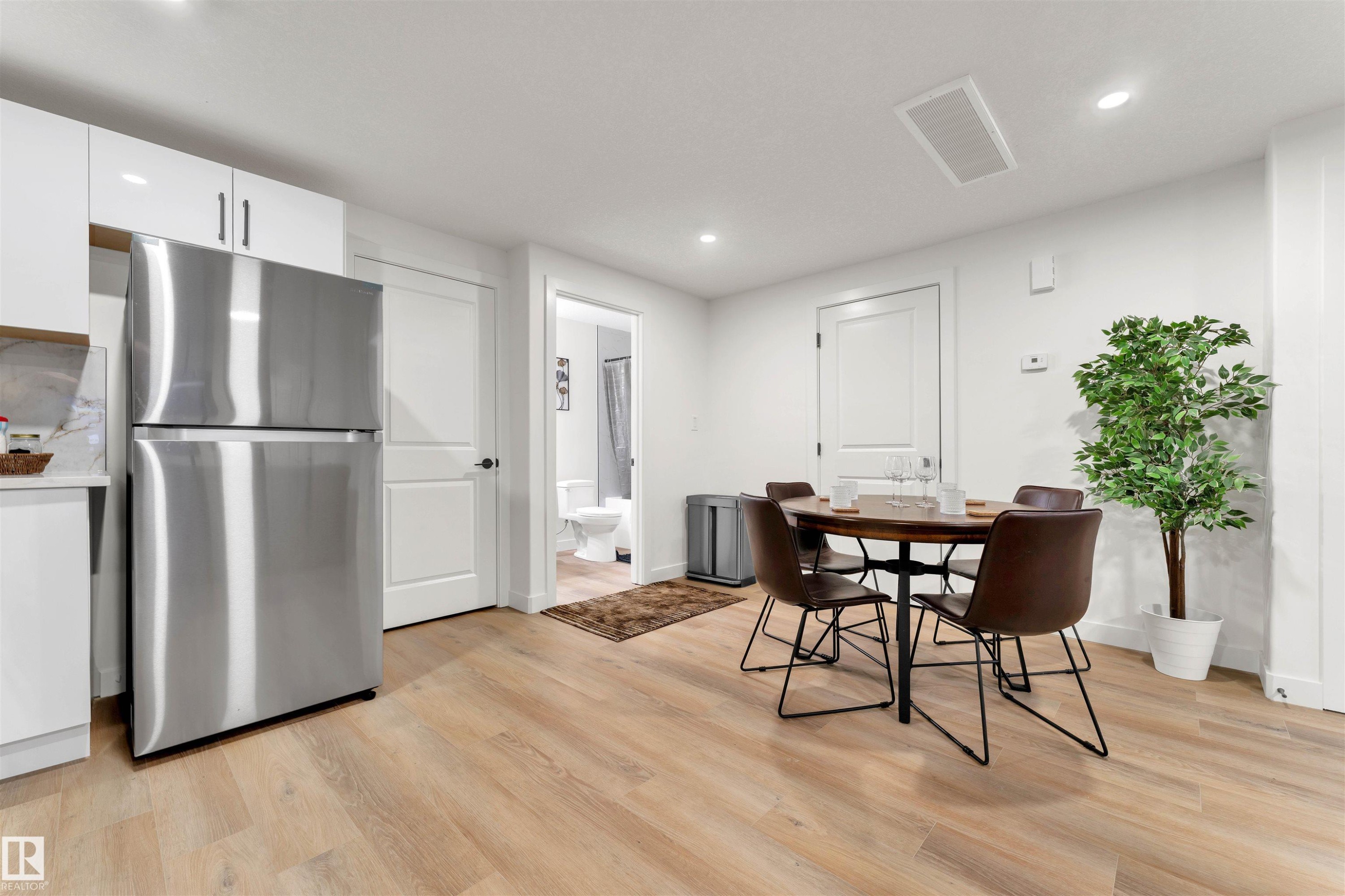 Open-concept living area featuring light wood-finish flooring, white walls, and recessed lighting - 403 Pine Point, Leduc, AB