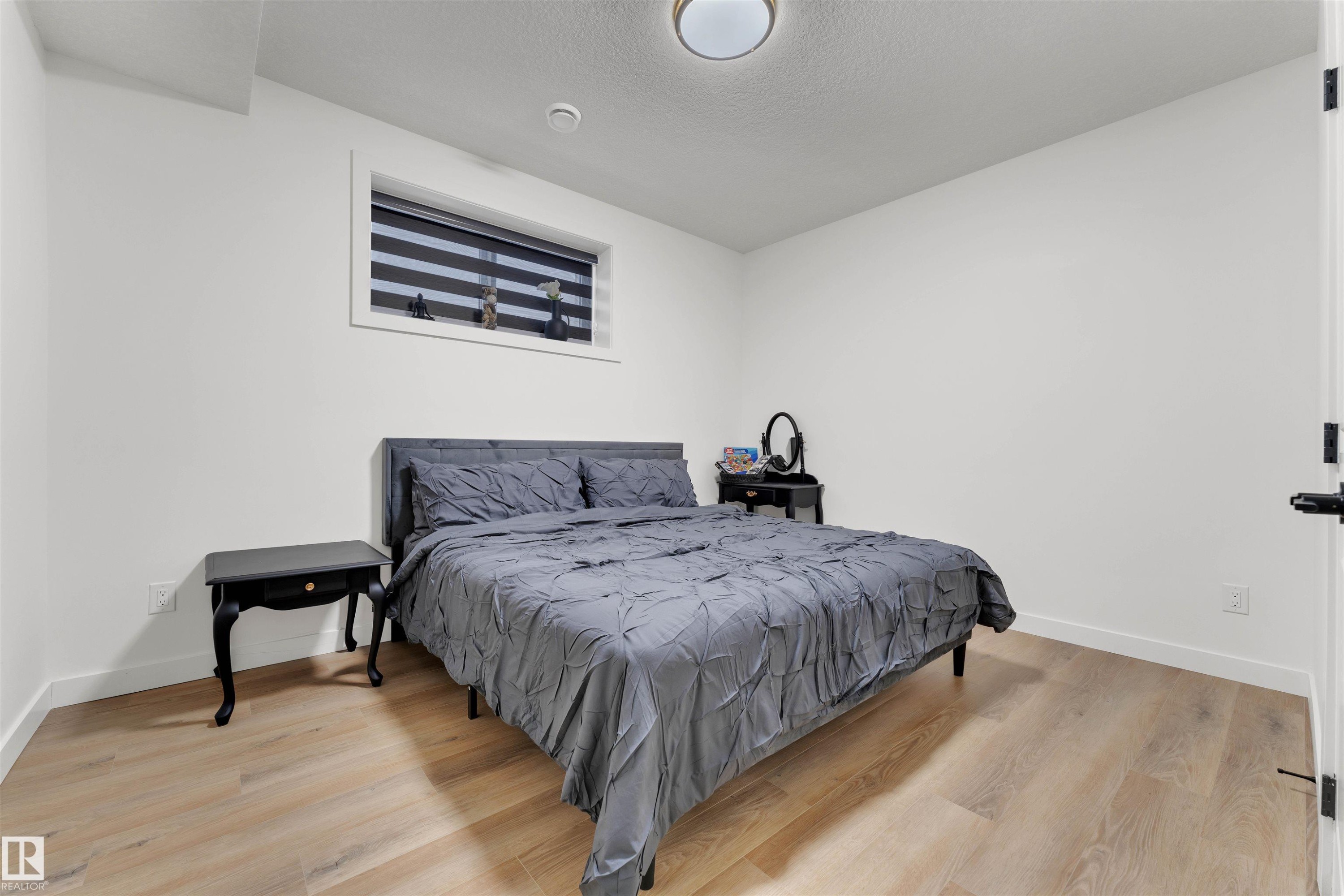 Room featuring wood-finish flooring, white baseboards, and a window with horizontal blinds - 403 Pine Point, Leduc, AB