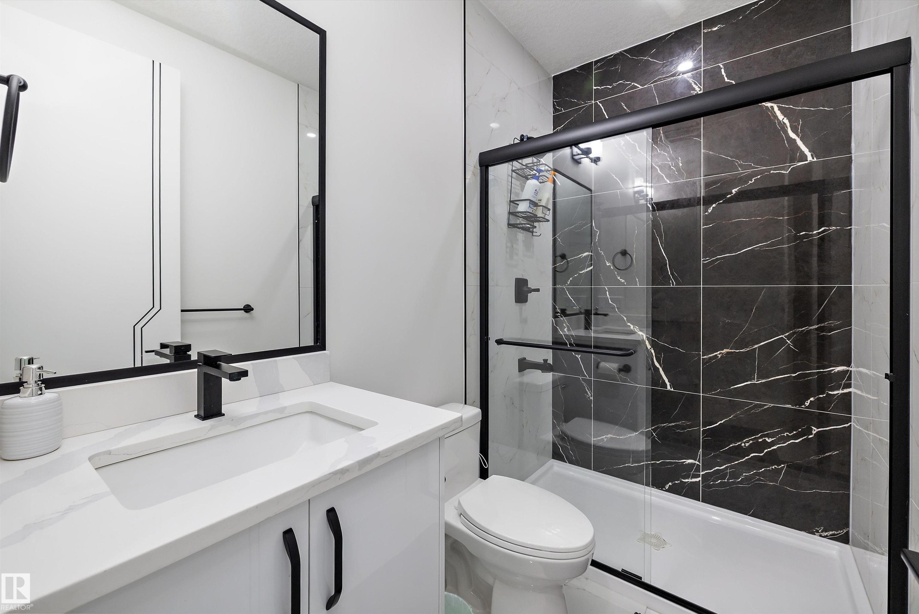 Bathroom featuring a white vanity with an integrated sink, a quartz-finish countertop, and matte black fixtures - 403 Pine Point, Leduc, AB