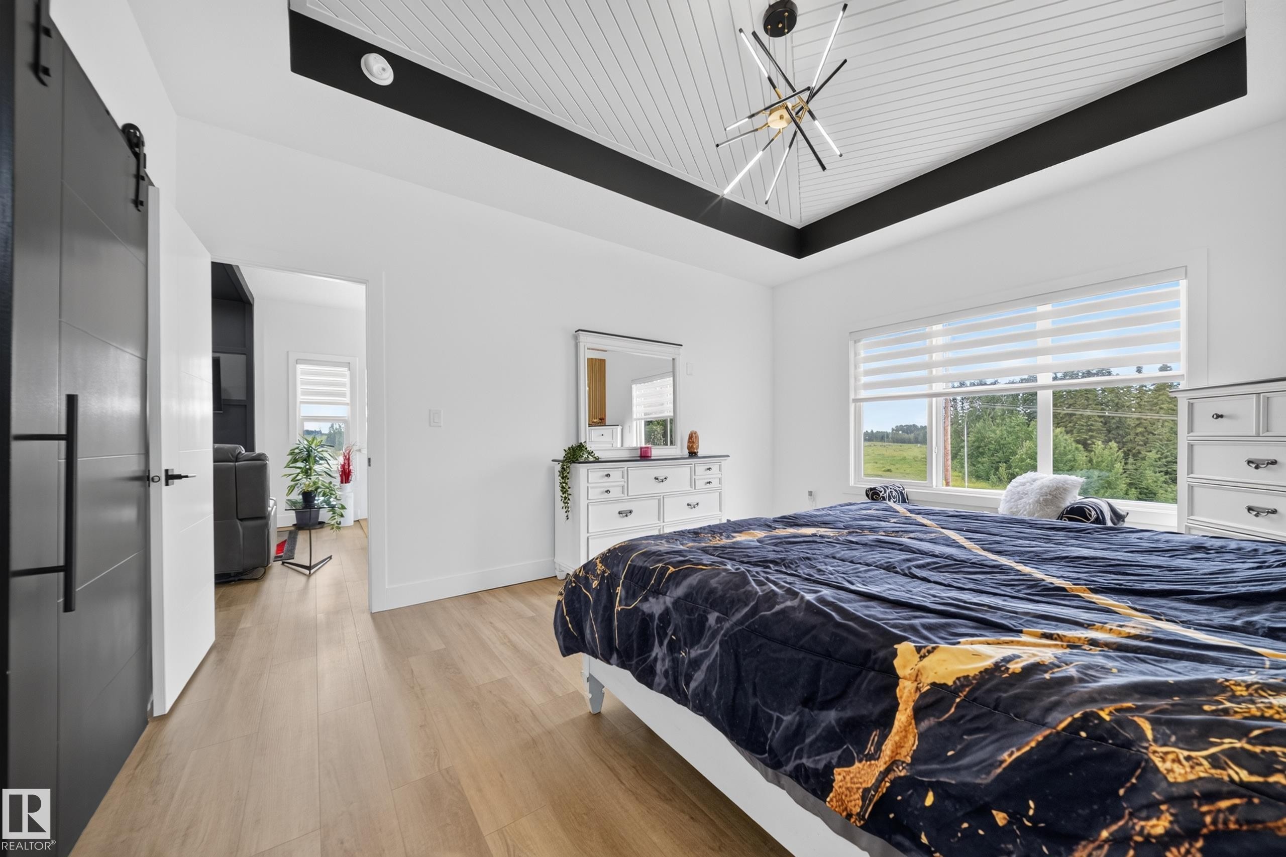 Room featuring wood-finish flooring, a white tray ceiling with black beams and white tongue-and-groove paneling, and a modern ceiling light fixture - 626 Astoria Way, Devon, AB