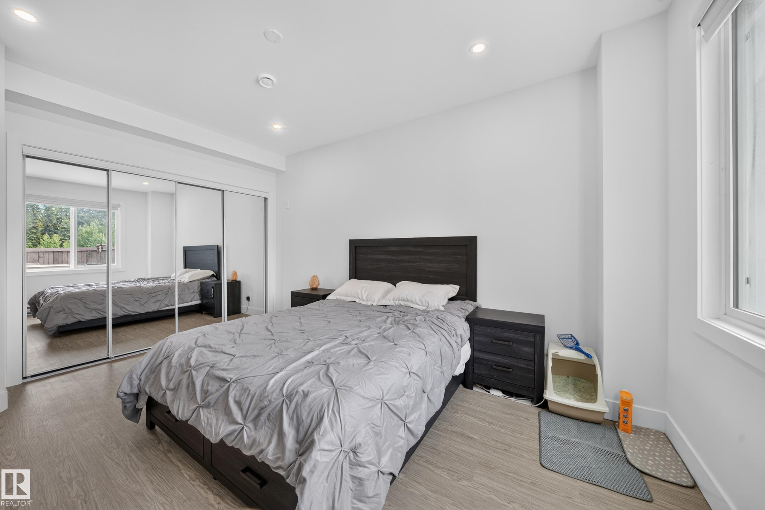 Bedroom featuring wood-finish flooring, recessed lighting, white walls, a window with a roller shade, and sliding mirrored closet doors - 626 Astoria Way, Devon, AB