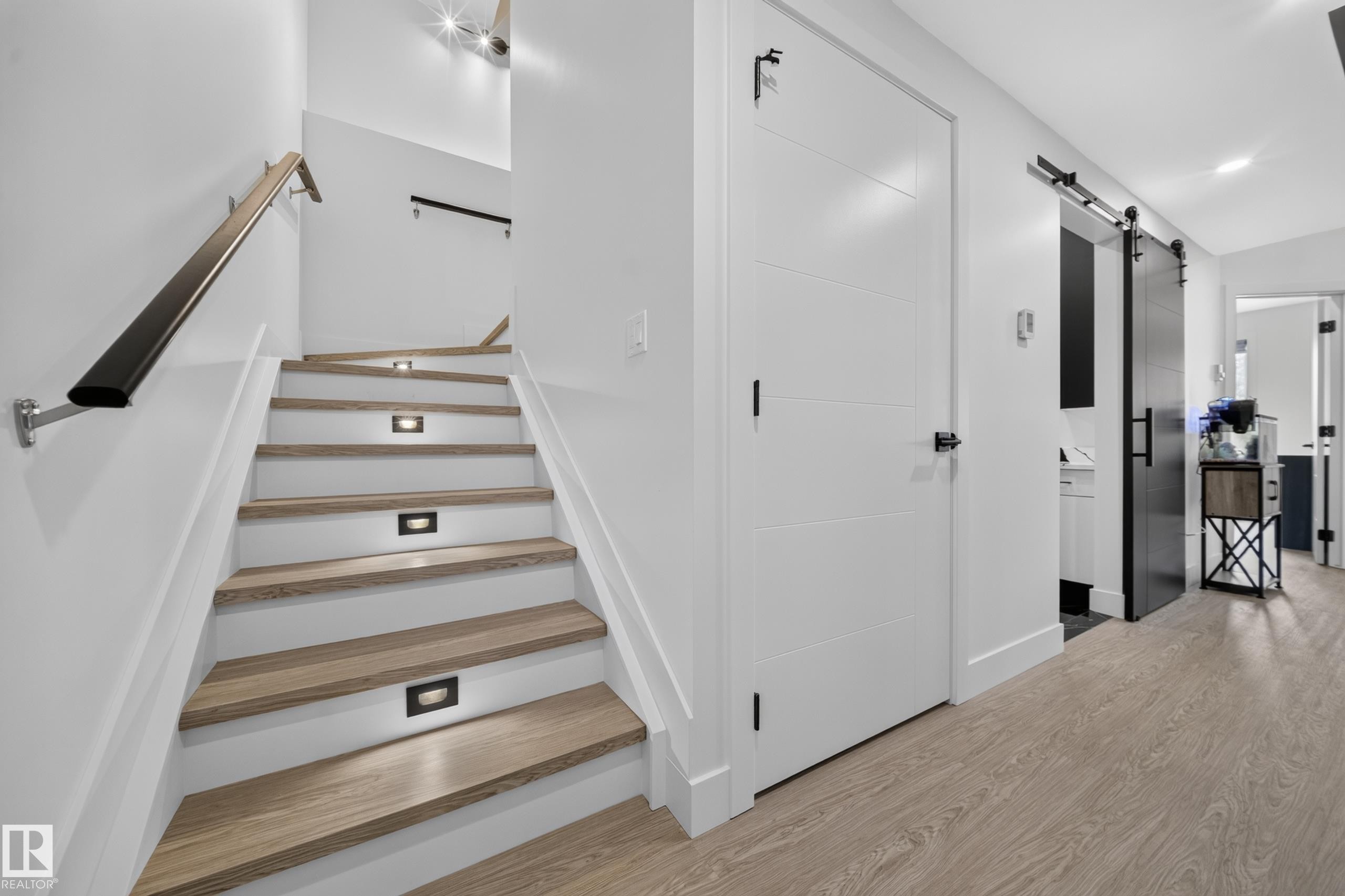 Staircase featuring wood-finish treads, recessed step lighting, and a black handrail - 626 Astoria Way, Devon, AB