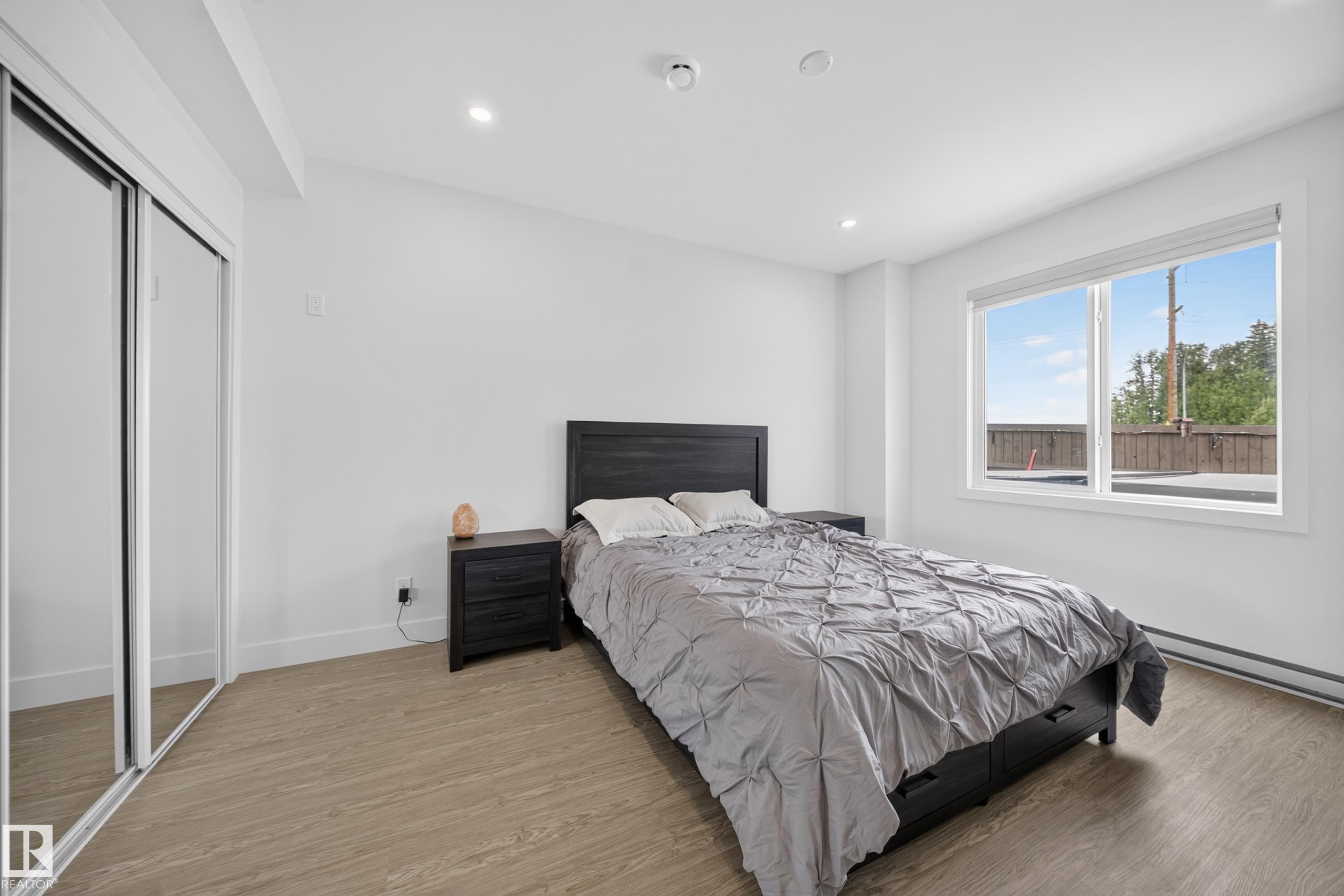 Bedroom featuring light wood-finish flooring, recessed lighting, and a large window with white trim - 626 Astoria Way, Devon, AB