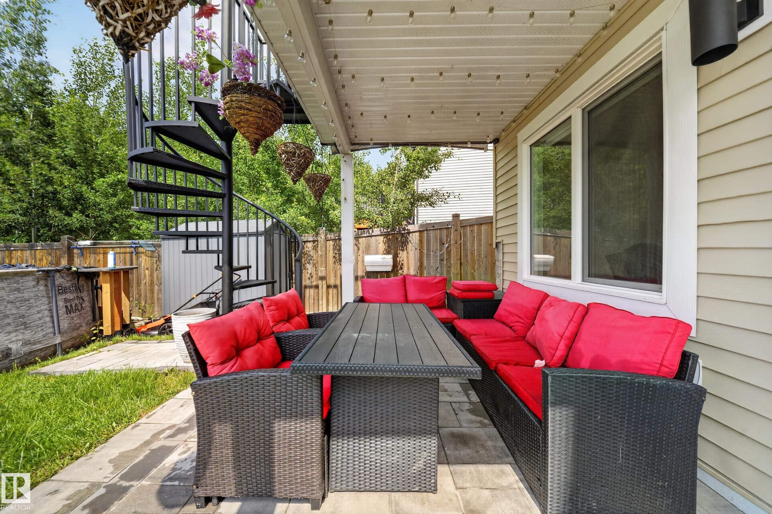 Covered patio area featuring a spiral staircase, stone paver flooring, and beige horizontal siding - 626 Astoria Way, Devon, AB