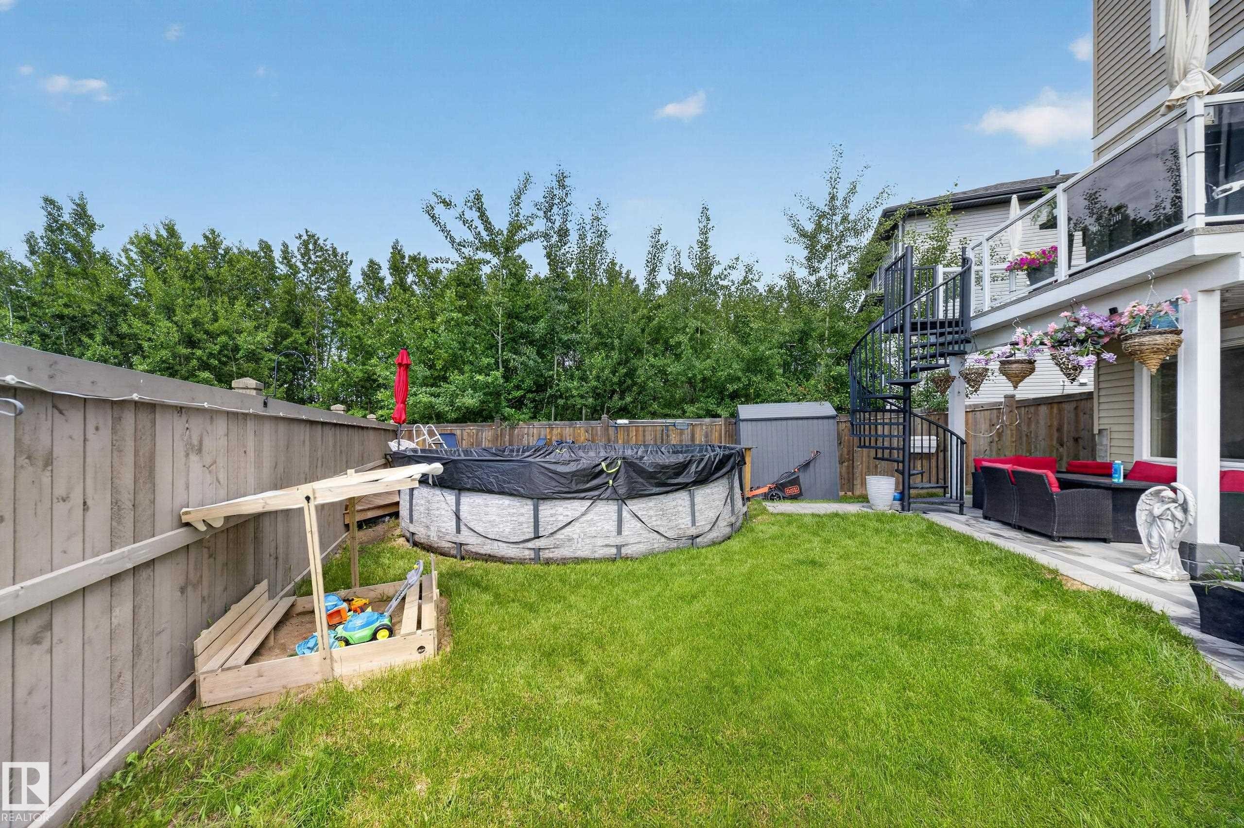Expansive backyard featuring a manicured lawn, a full wooden fence, and mature trees providing privacy - 626 Astoria Way, Devon, AB