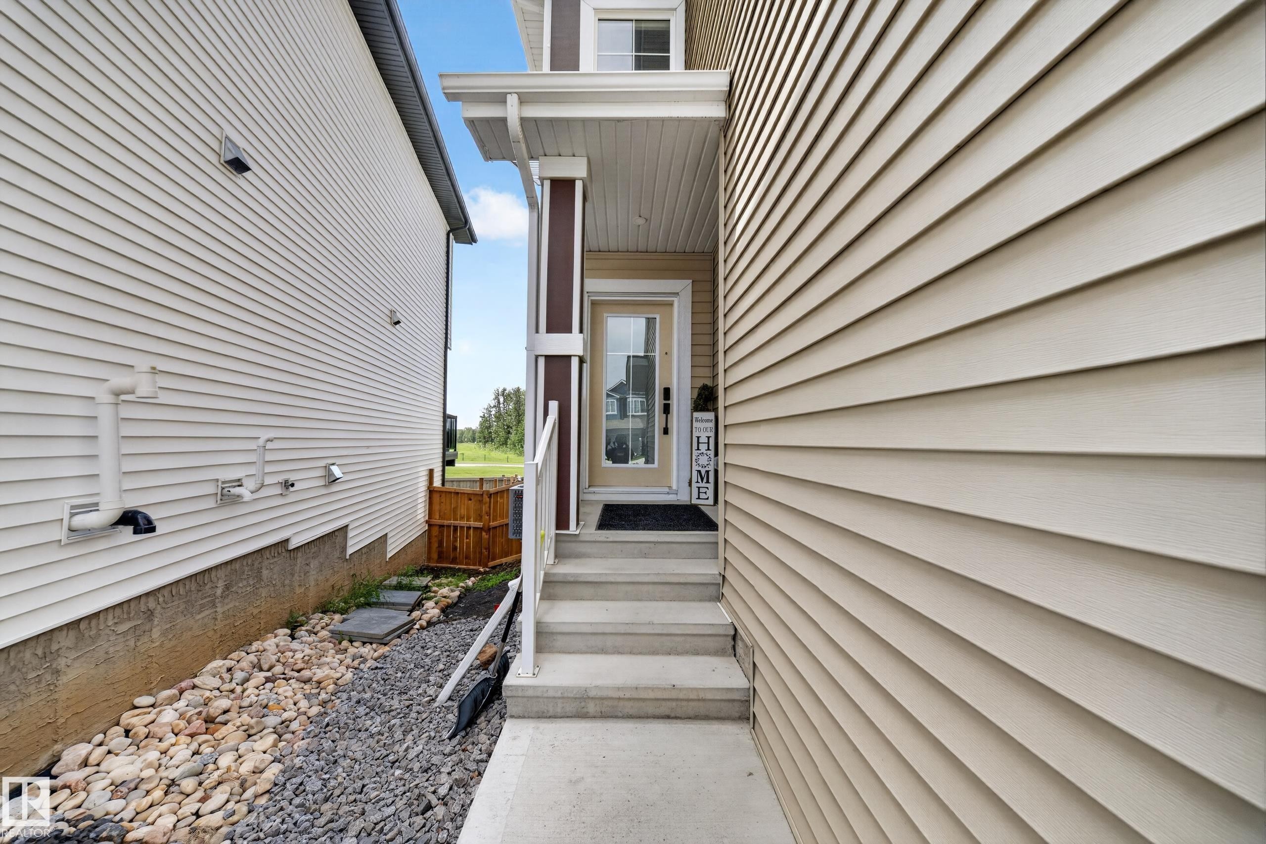 Front entry featuring a covered porch, solid core door with sidelight, and concrete steps - 626 Astoria Way, Devon, AB