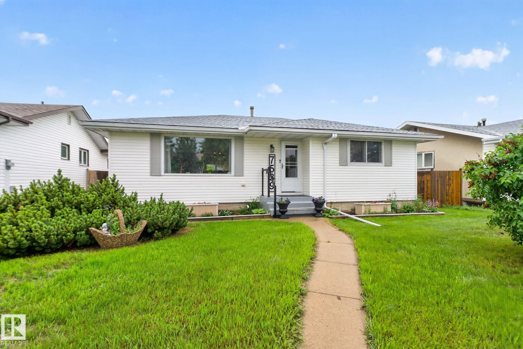 White siding exterior featuring a grey shingle roof and a concrete pathway - 7539 149A Avenue Nw, Edmonton, AB - Outdoor