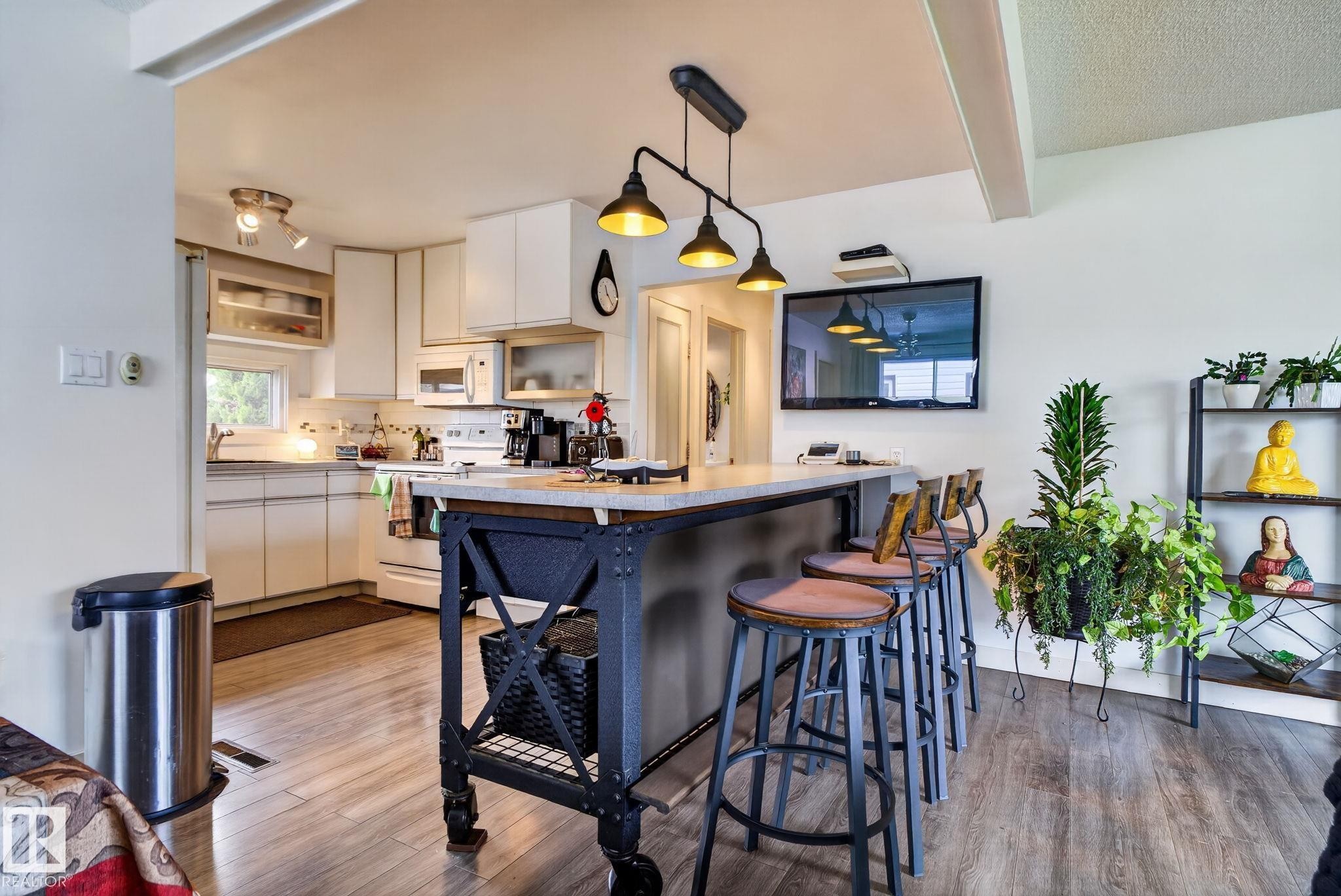 Kitchen featuring white cabinetry, a built-in microwave, and wood-finish flooring - 7539 149A Avenue Nw, Edmonton, AB - Indoor