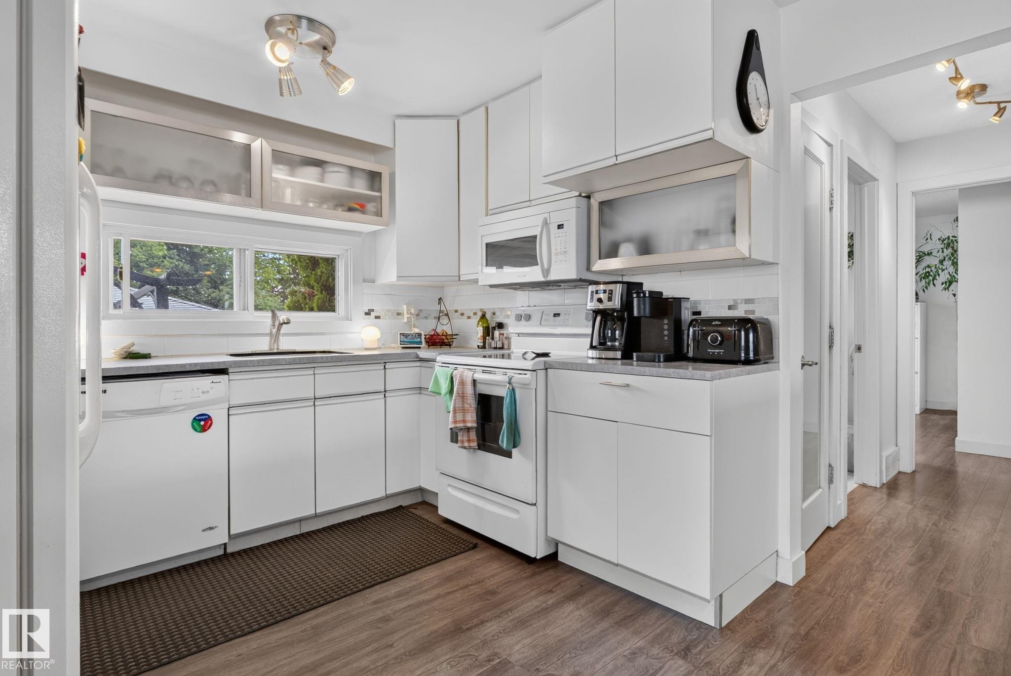 White kitchen featuring shaker-style cabinetry, wood-finish flooring, recessed lighting, and a window above the sink - 7539 149A Avenue Nw, Edmonton, AB - Indoor Photo Showing Kitchen