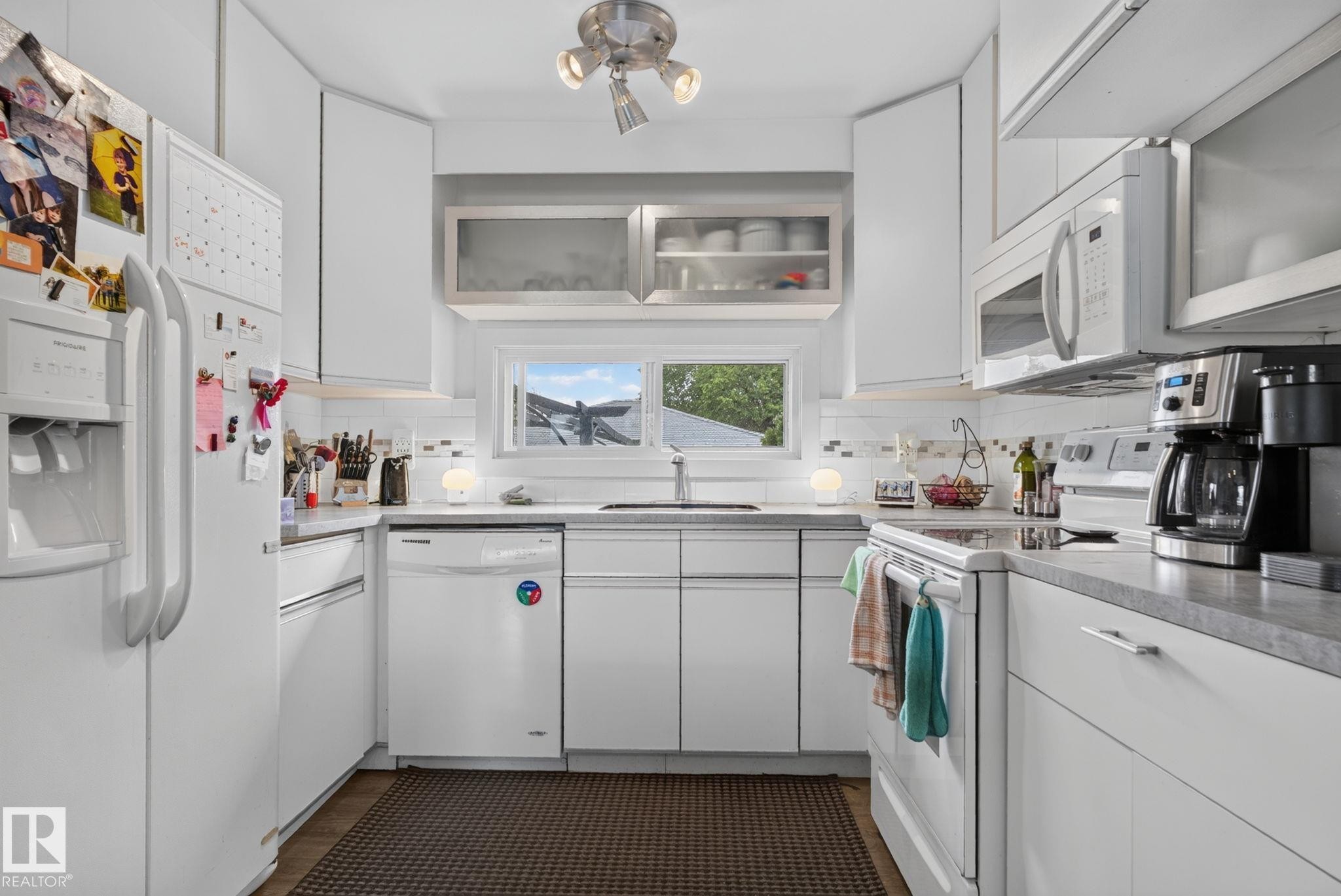 Bright kitchen featuring white cabinetry, light countertops, and a white subway tile backsplash - 7539 149A Avenue Nw, Edmonton, AB - Indoor Photo Showing Kitchen