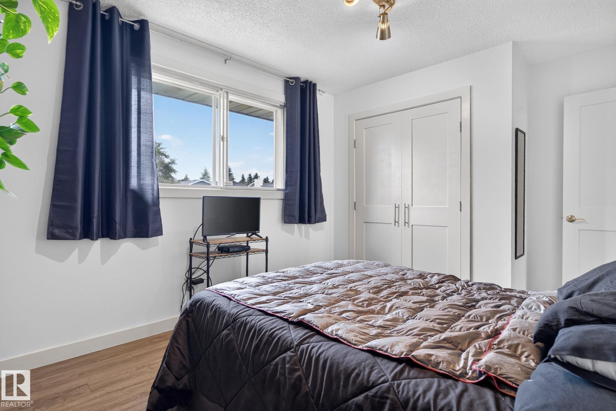 Bedroom featuring white walls, wood-finish flooring, and a double-pane window - 7539 149A Avenue Nw, Edmonton, AB - Indoor Photo Showing Bedroom