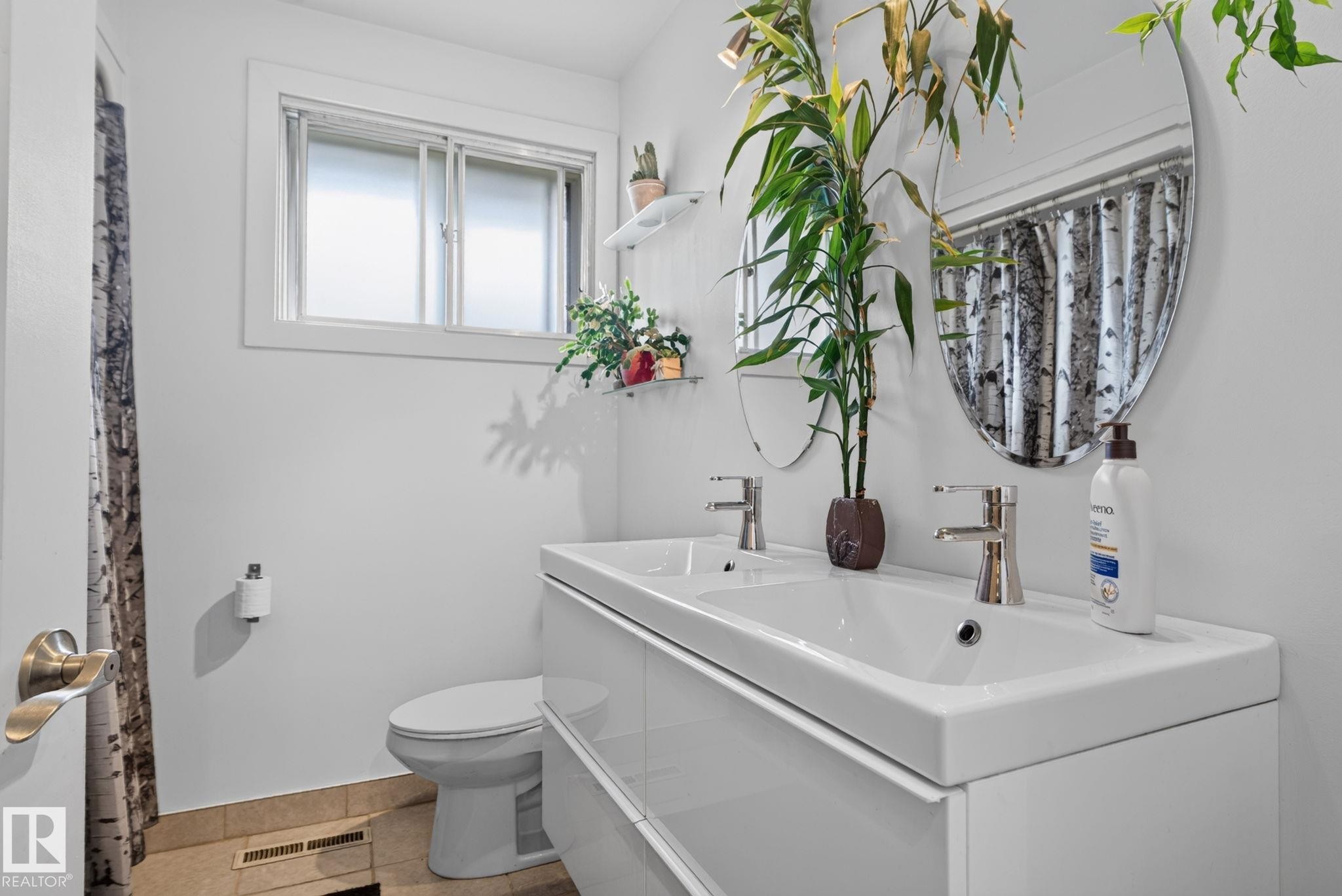 Bathroom with a modern double vanity featuring dual sinks and chrome faucets - 7539 149A Avenue Nw, Edmonton, AB - Indoor Photo Showing Bathroom