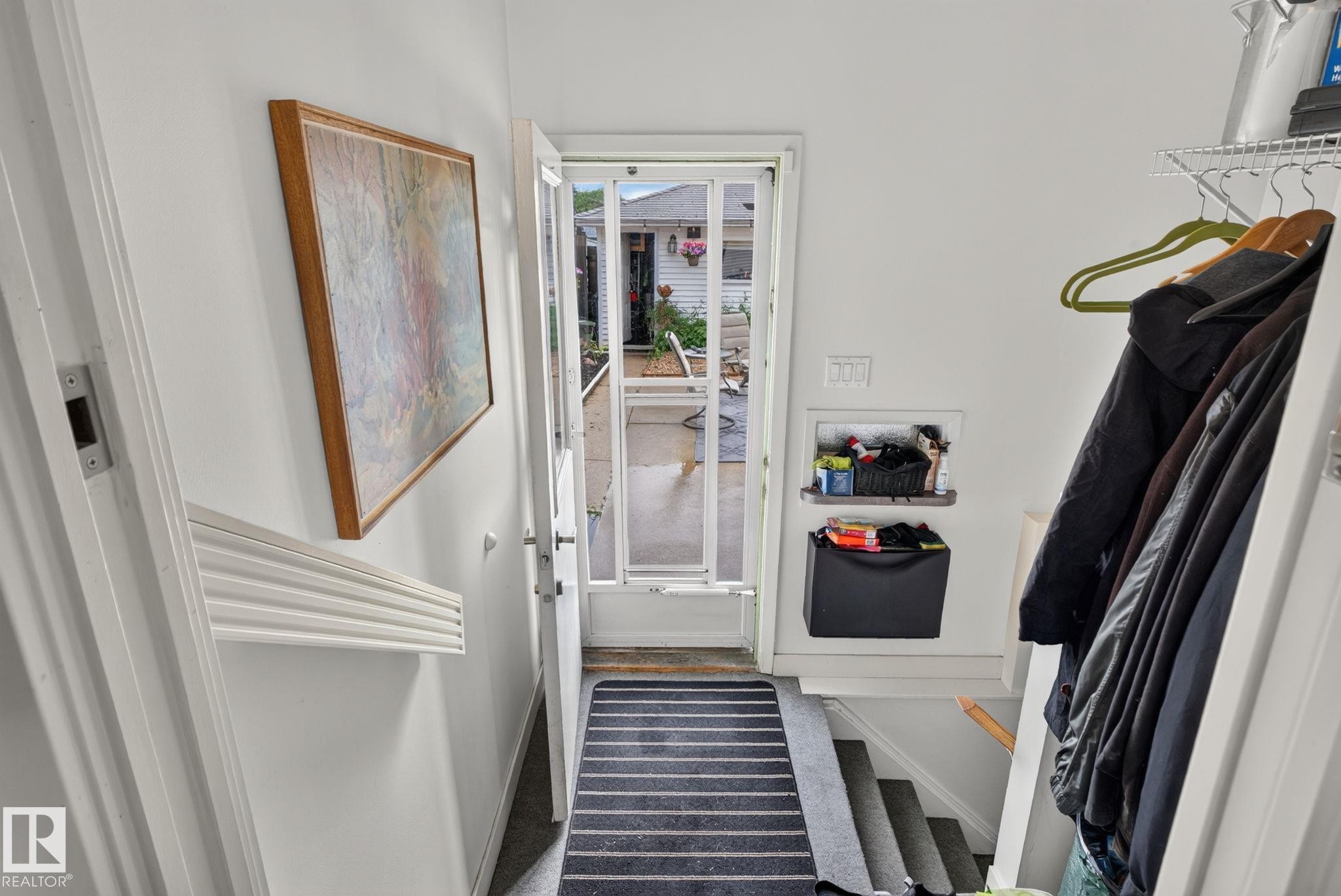 Entryway featuring a white storm door, striped floor mat, and built-in shelving - 7539 149A Avenue Nw, Edmonton, AB - Indoor