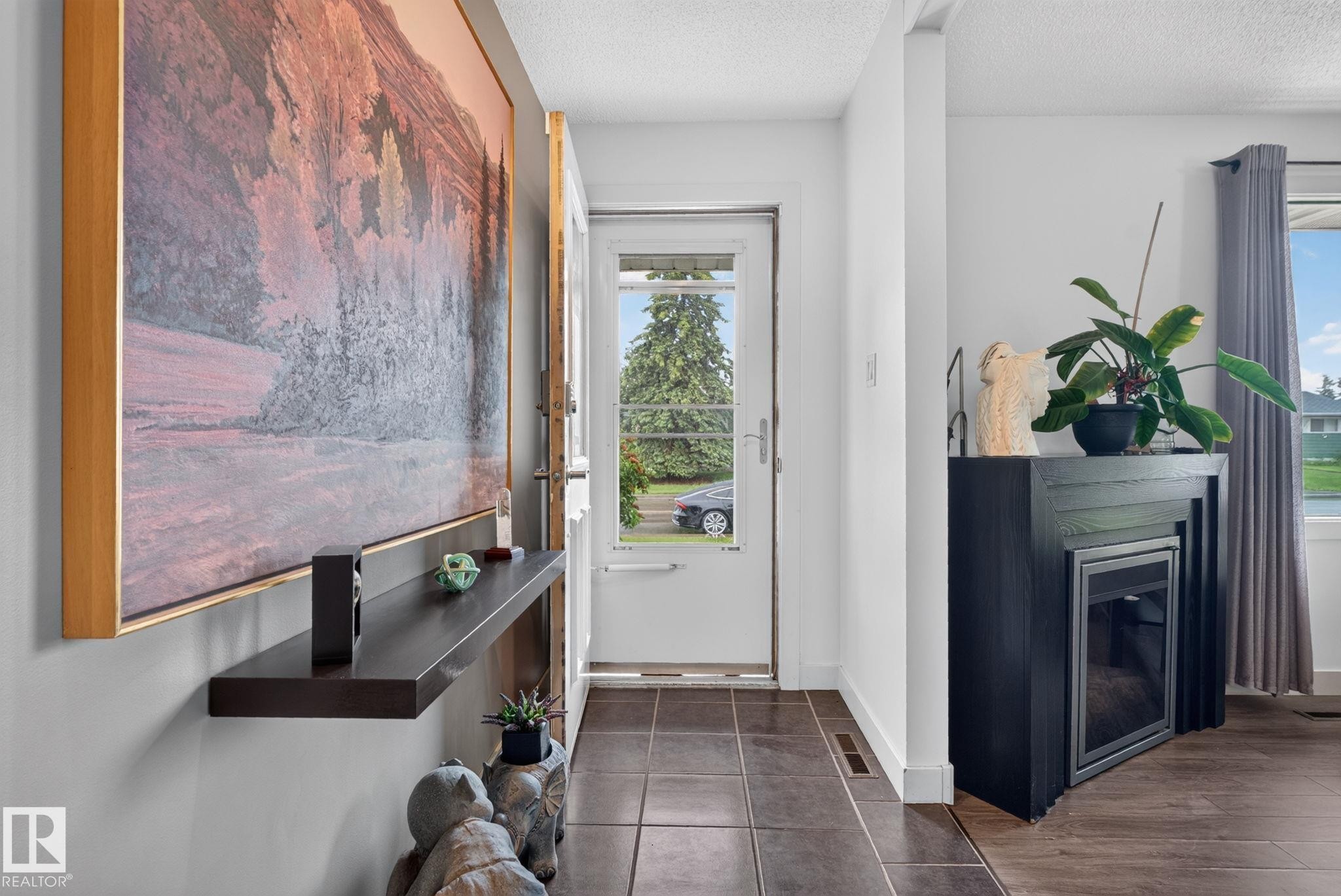 Entryway featuring tile flooring, a glass-paneled entry door, a dark wood built-in shelving unit, and a built-in electric fireplace with a dark wood mantel - 7539 149A Avenue Nw, Edmonton, AB - Indoor Photo Showing Other Room